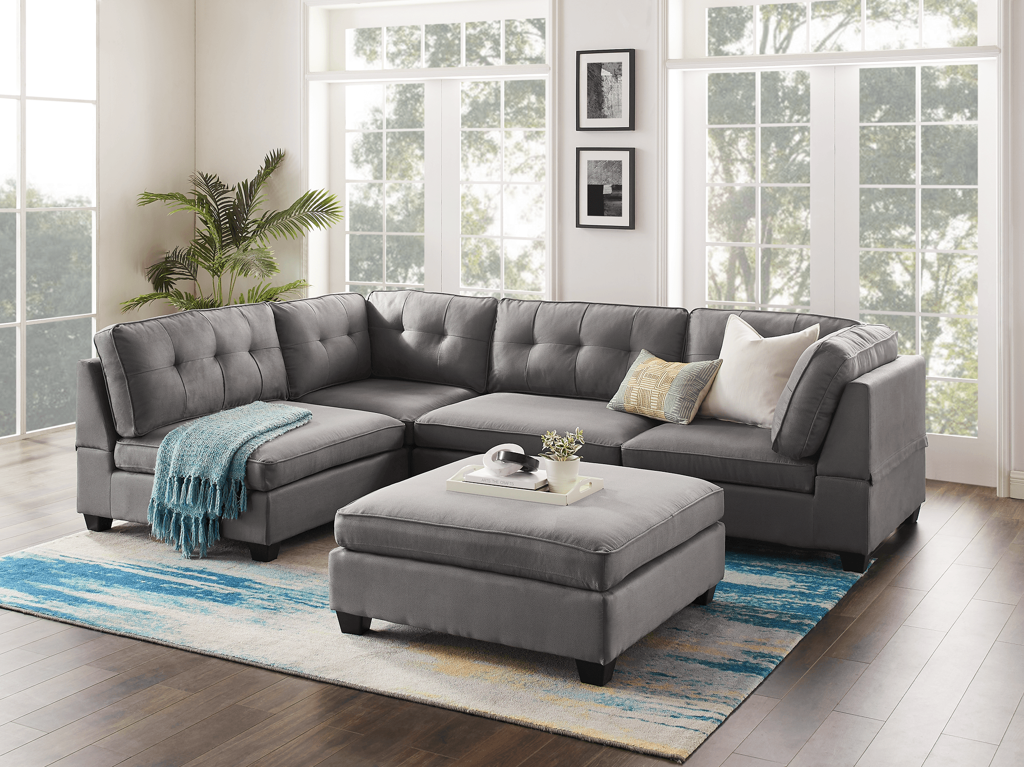 Modern grey sectional sofa with tufted cushions and ottoman in a bright living room