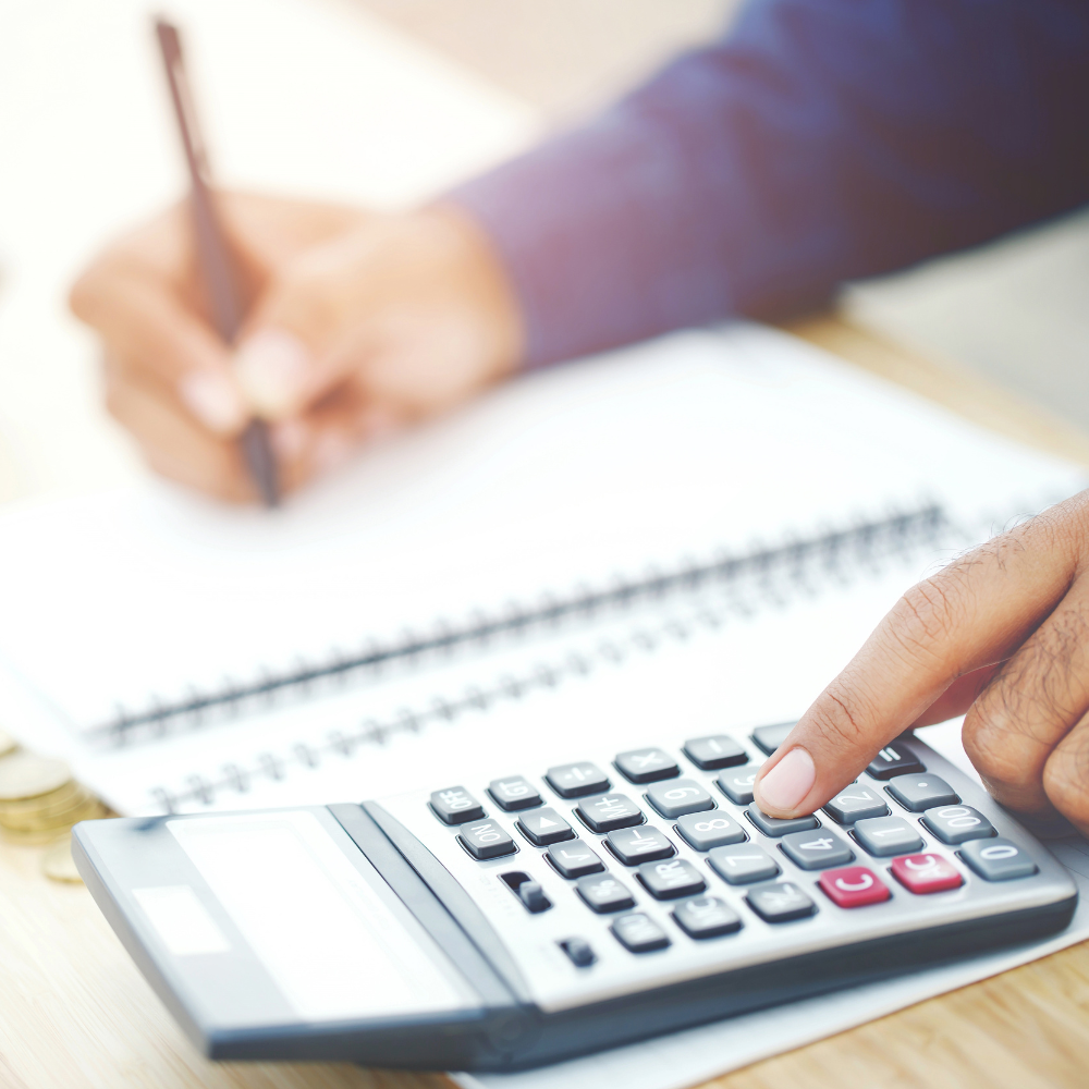 Person calculating furniture budget with calculator and notebook on desk