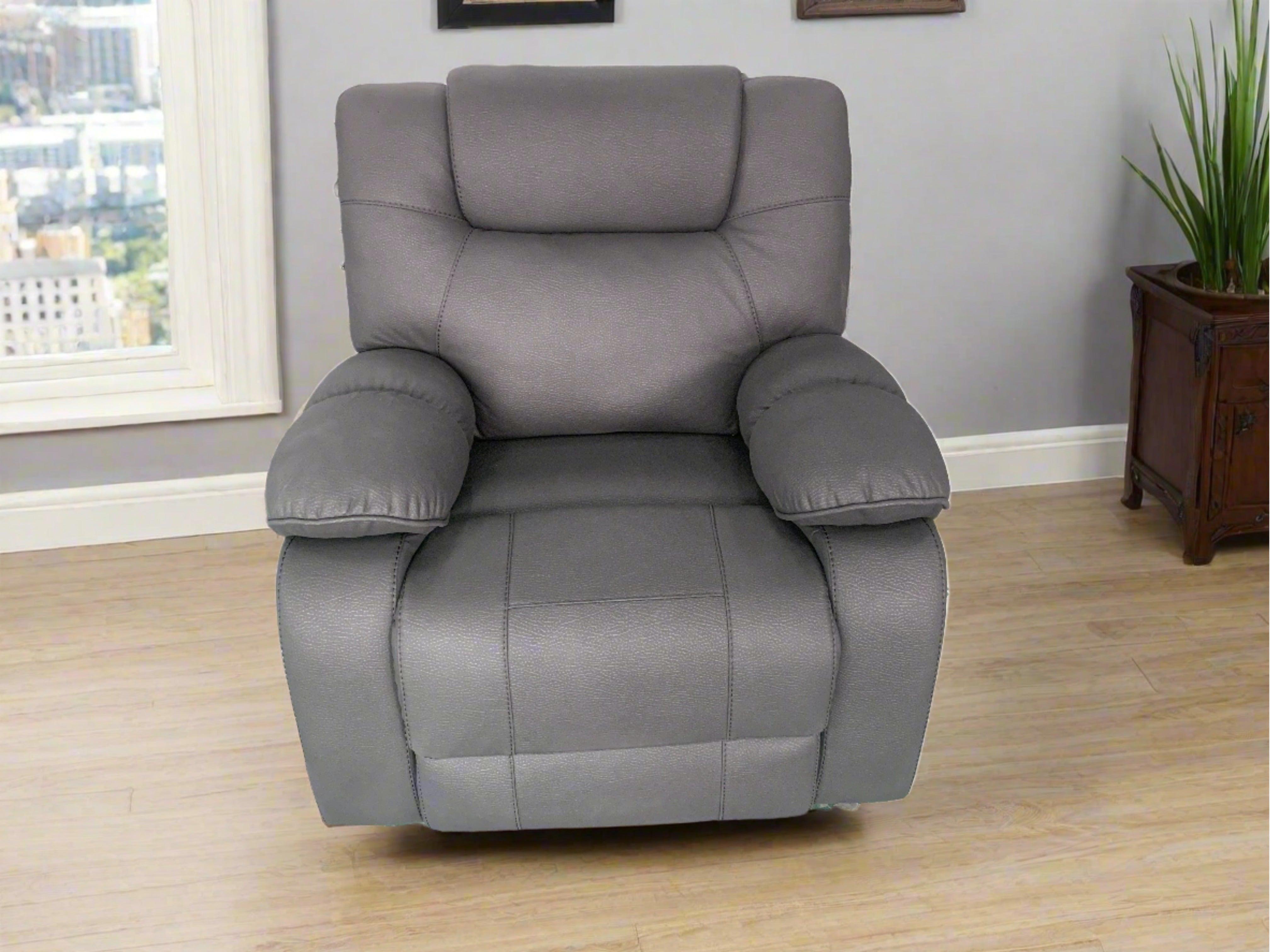 Modern grey recliner armchair in living room with wooden floor and indoor plant