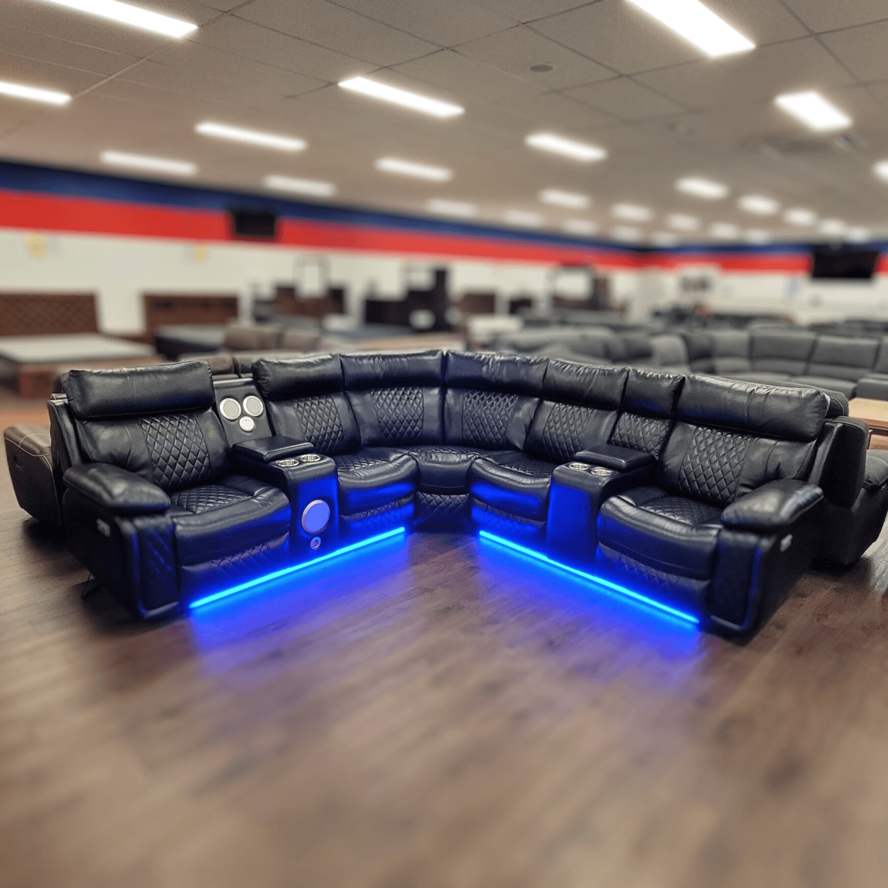 Black leather recliner sectional sofa with LED lighting and cup holders in a showroom