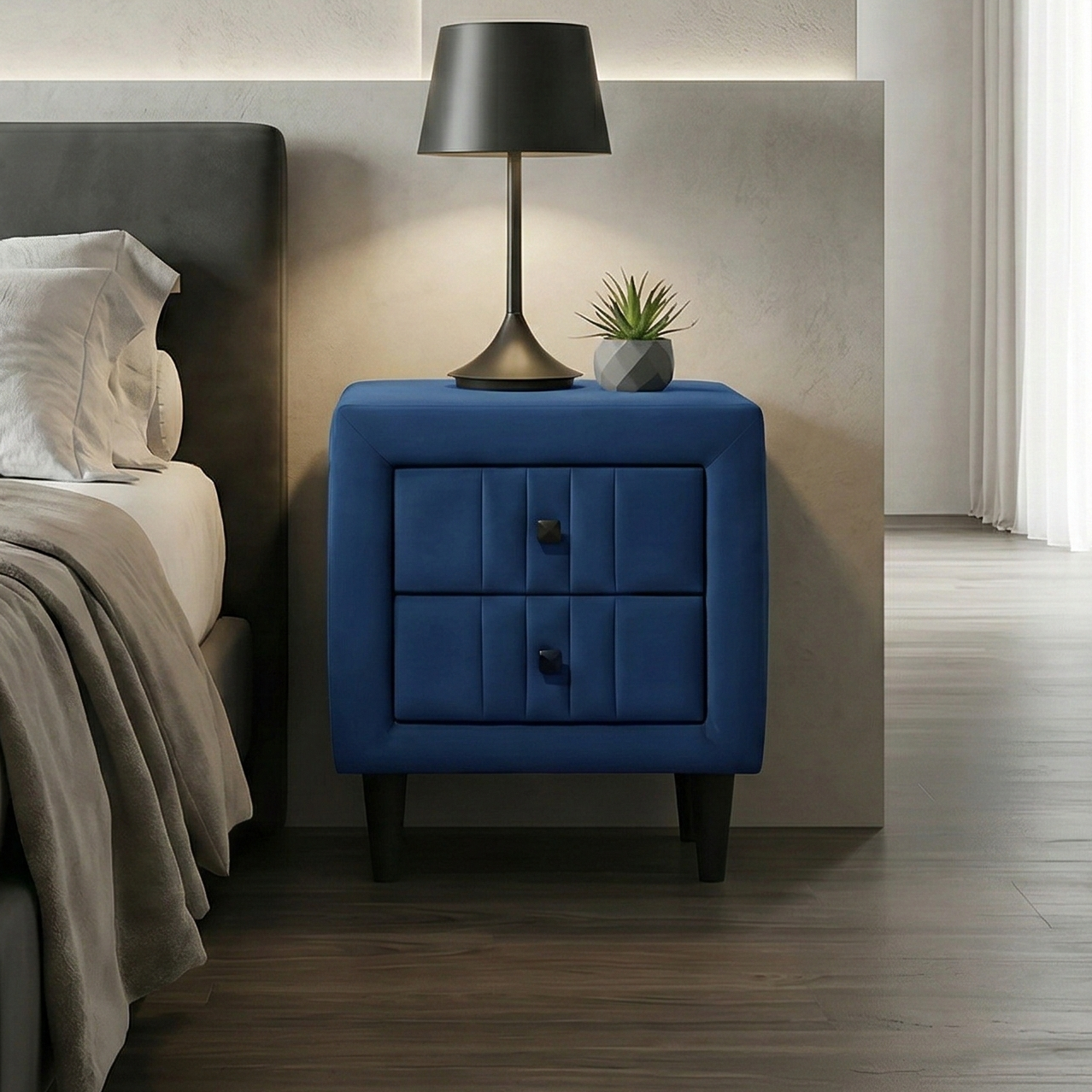 Modern bedside table with blue velvet fabric, nightstand, grey bed on the side, and abstract art on the wall.