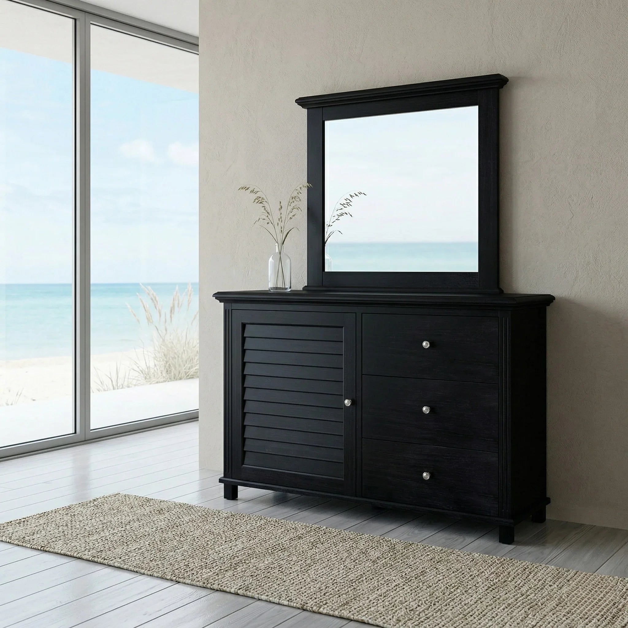 Black dresser with mirror in a room with large windows showing an ocean view.