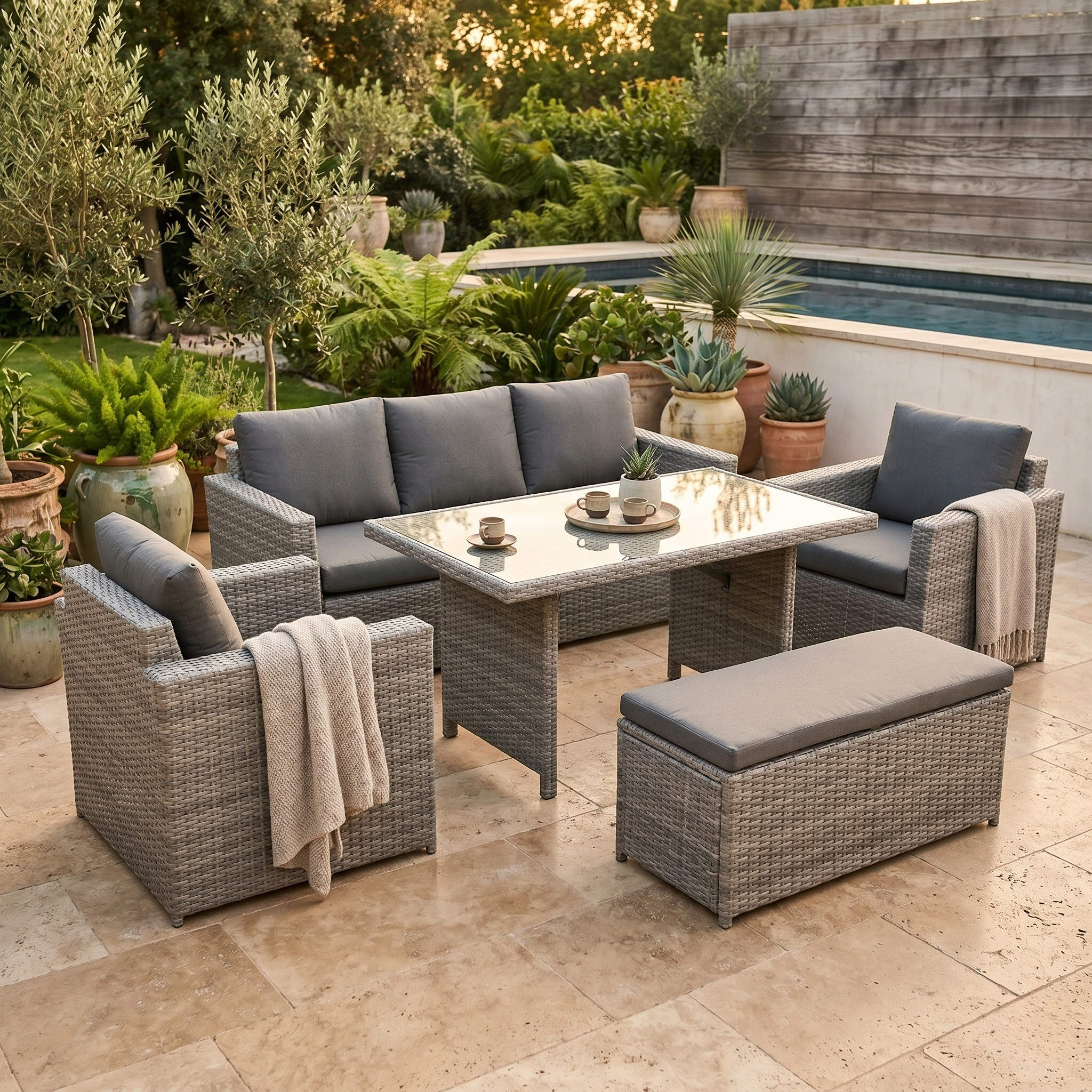Outdoor patio set with gray cushions and a coffee table in a garden setting.