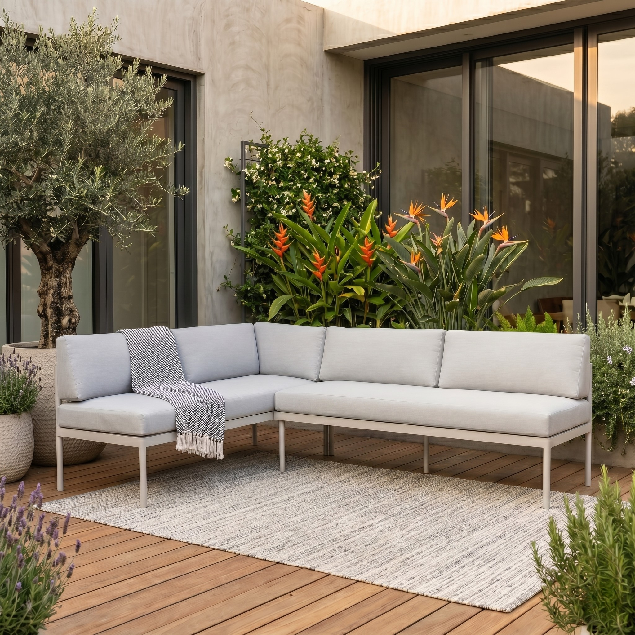 Outdoor patio with a sectional sofa, plants, and a rug on a wooden deck.