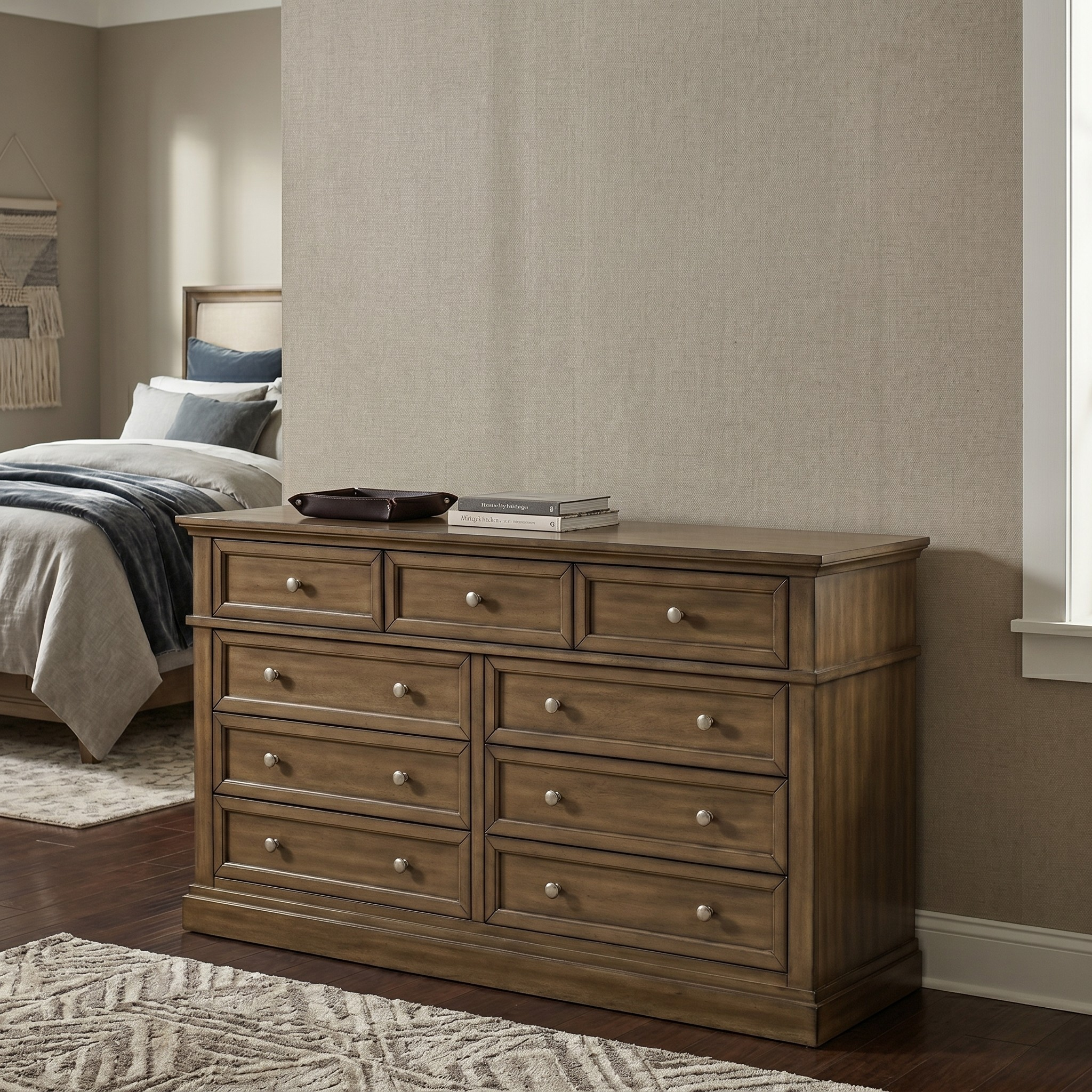 Wooden dresser in a bedroom setting with a bed and wall decor.