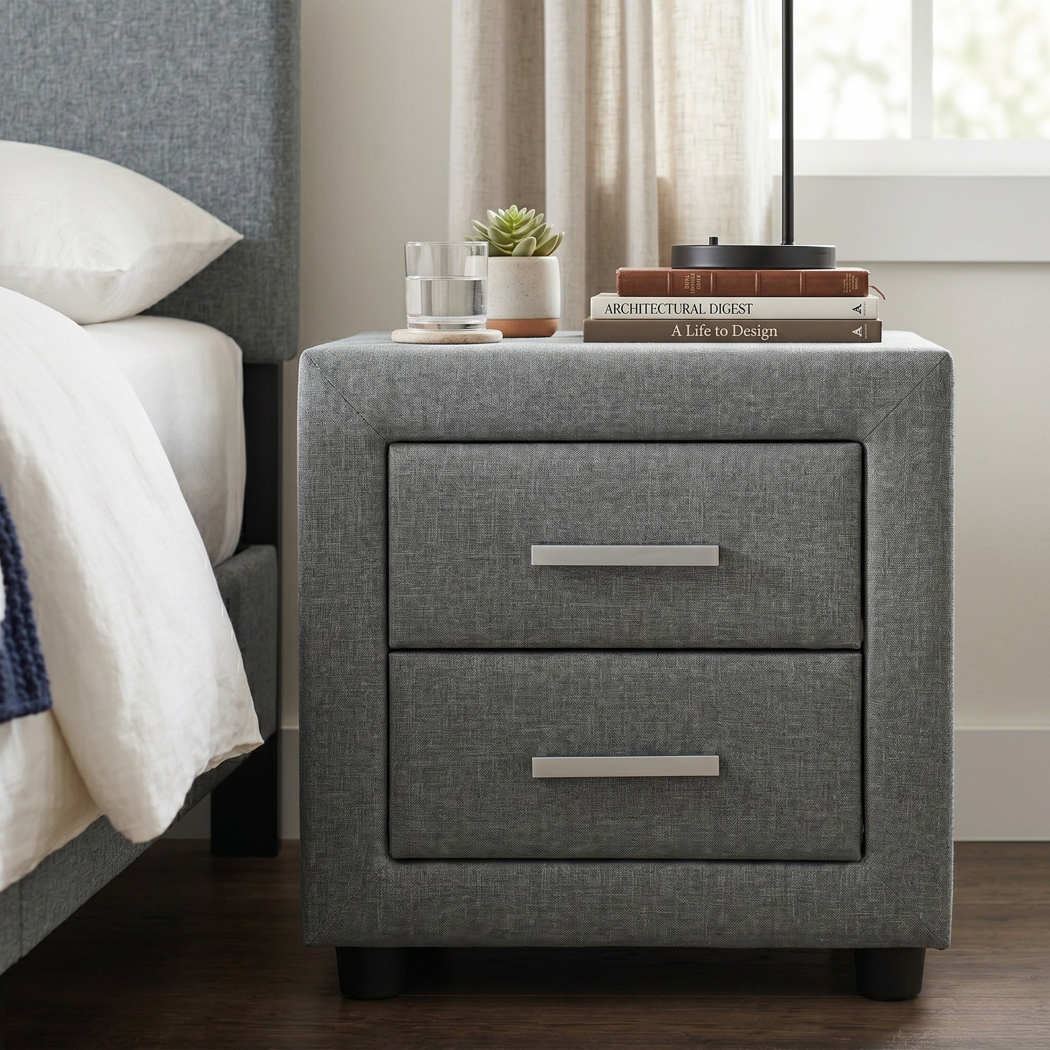 Gray nightstand with two drawers next to a bed in a bedroom setting.
