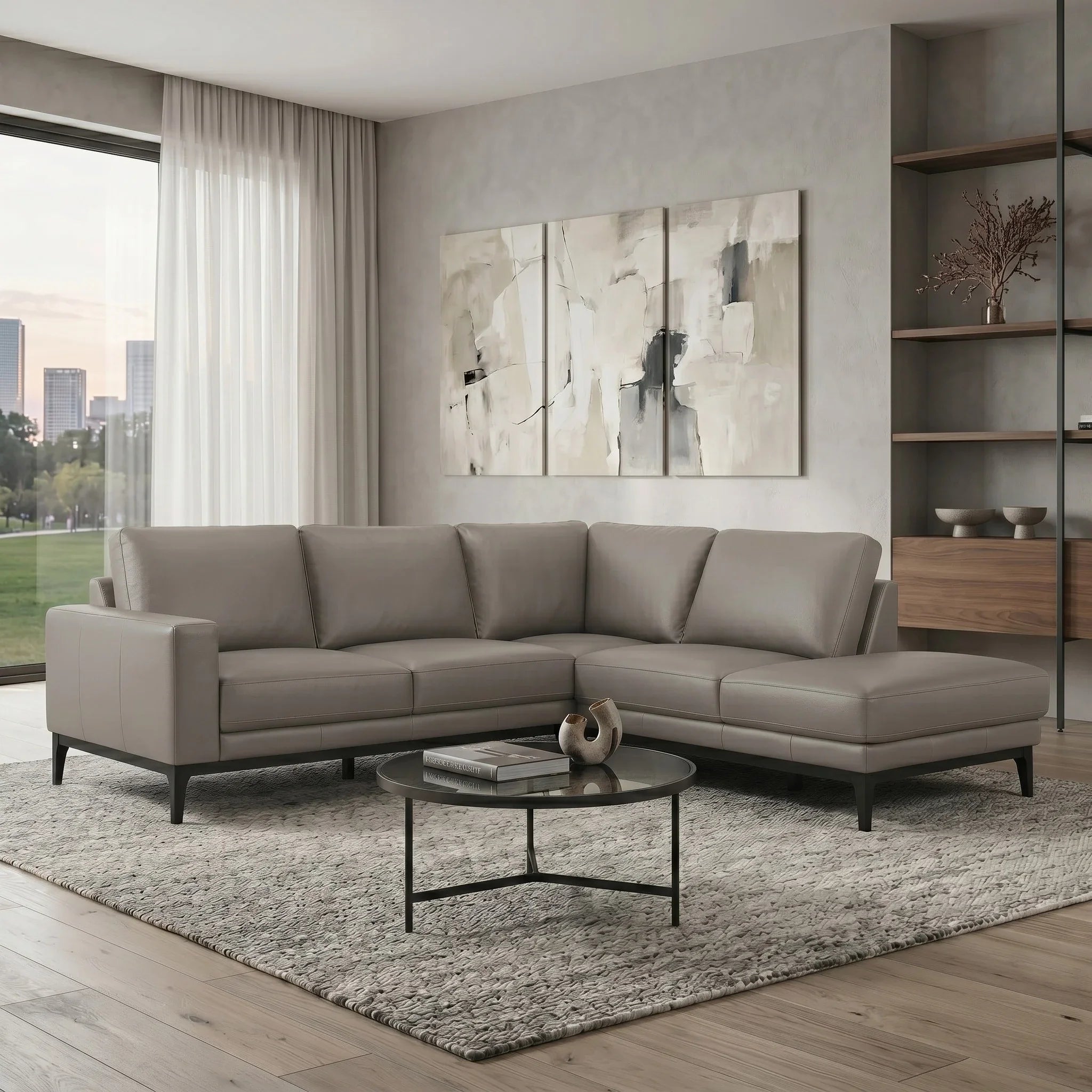 Modern living room with a gray sectional sofa, round coffee table, and abstract art on the wall.