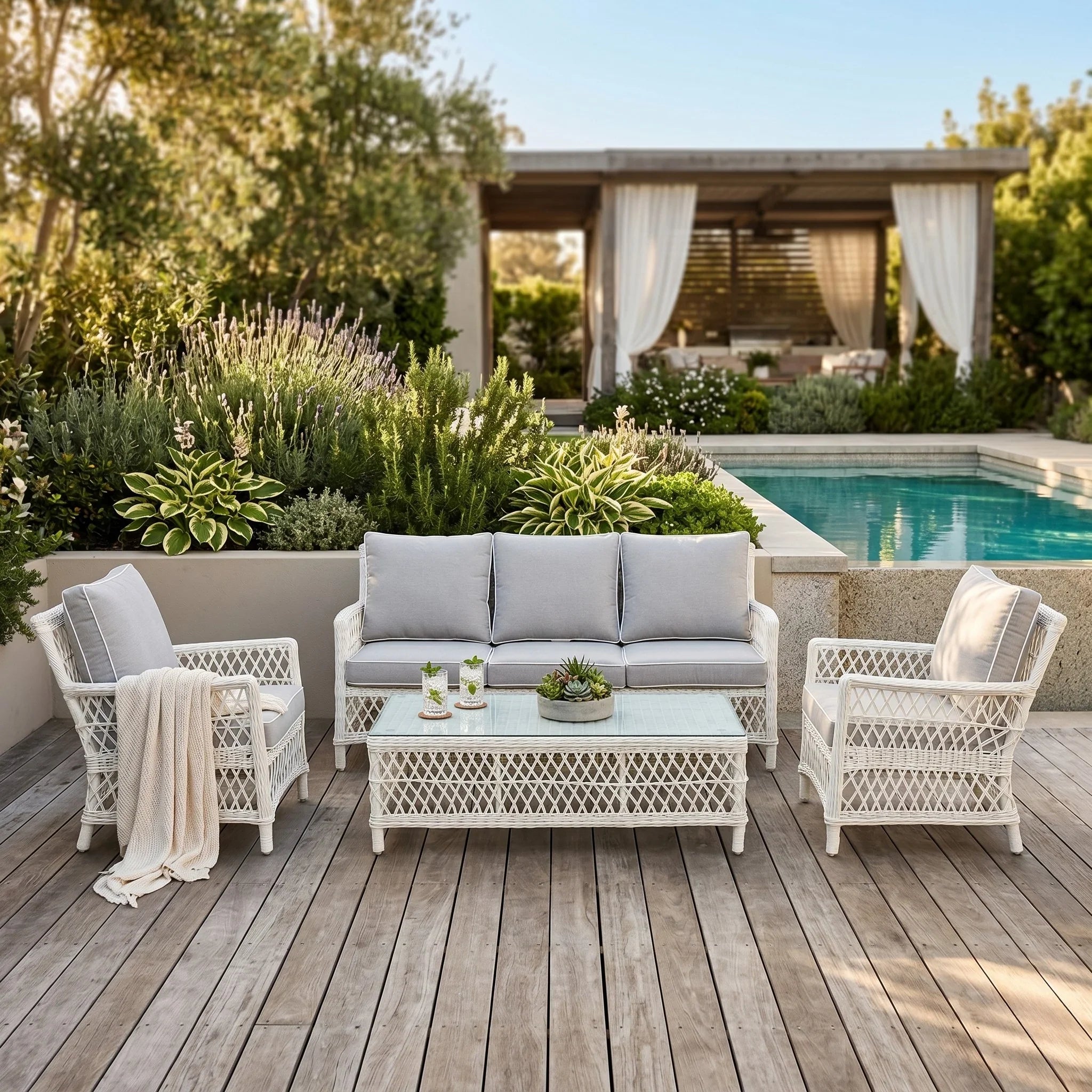Outdoor patio set with gray cushions and white wicker chairs by a pool