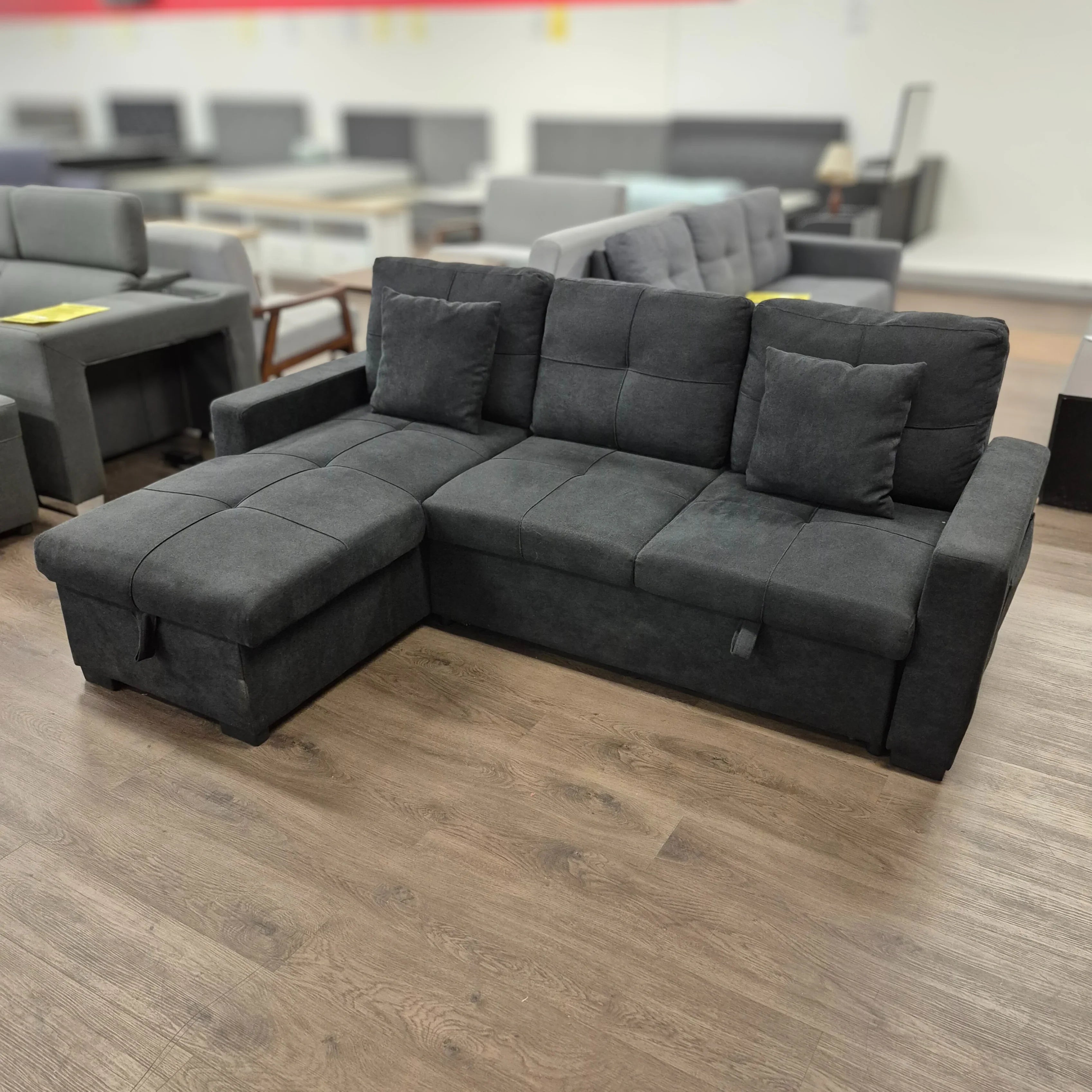 Modern black fabric sectional sofa with chaise and cushions in a furniture showroom