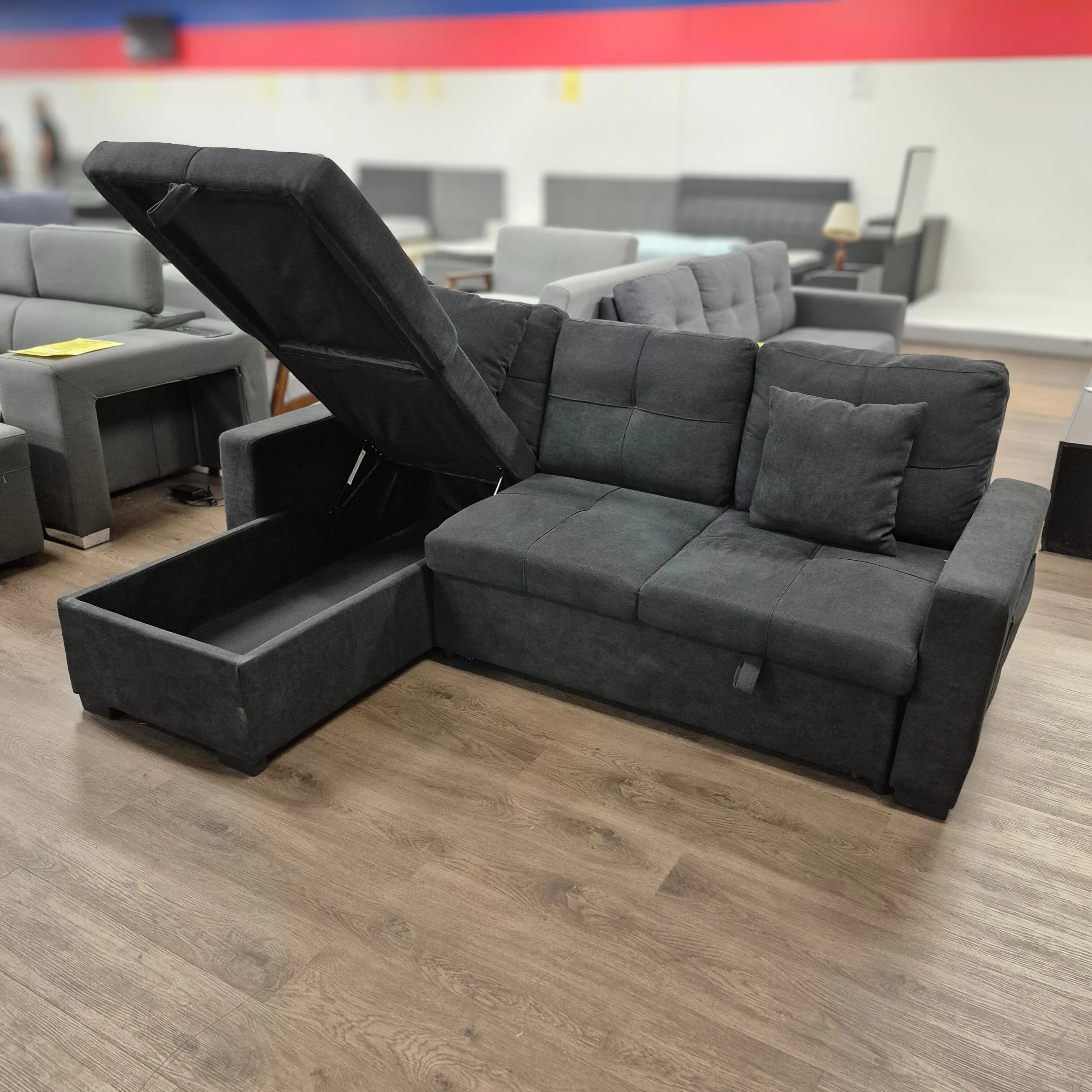 Black fabric sectional sofa with storage chaise in showroom on wood floor