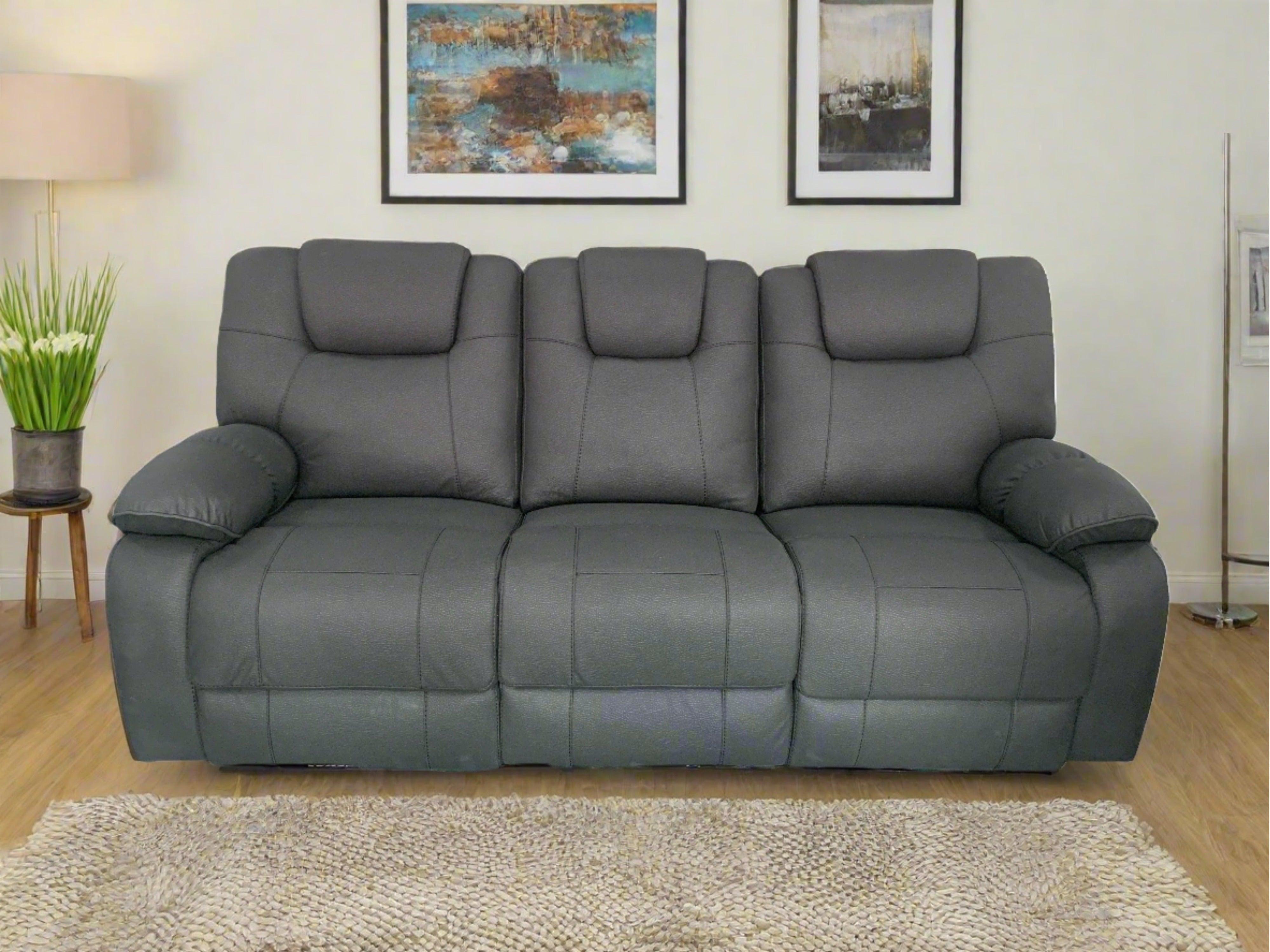 Modern grey three-seater recliner sofa in living room with decorative wall art and rug