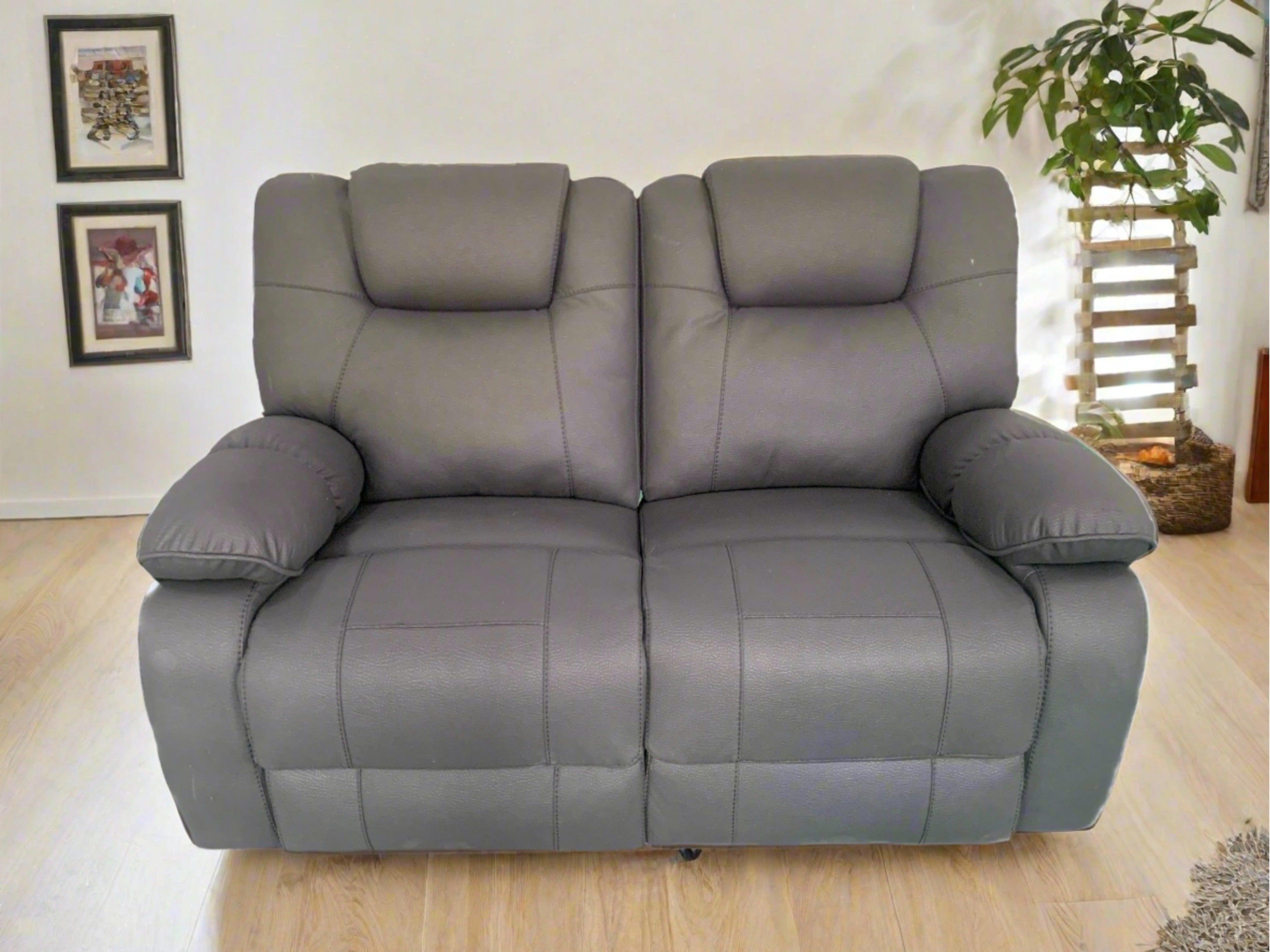 Modern grey two-seater recliner sofa in a cozy living room with wood flooring and decor