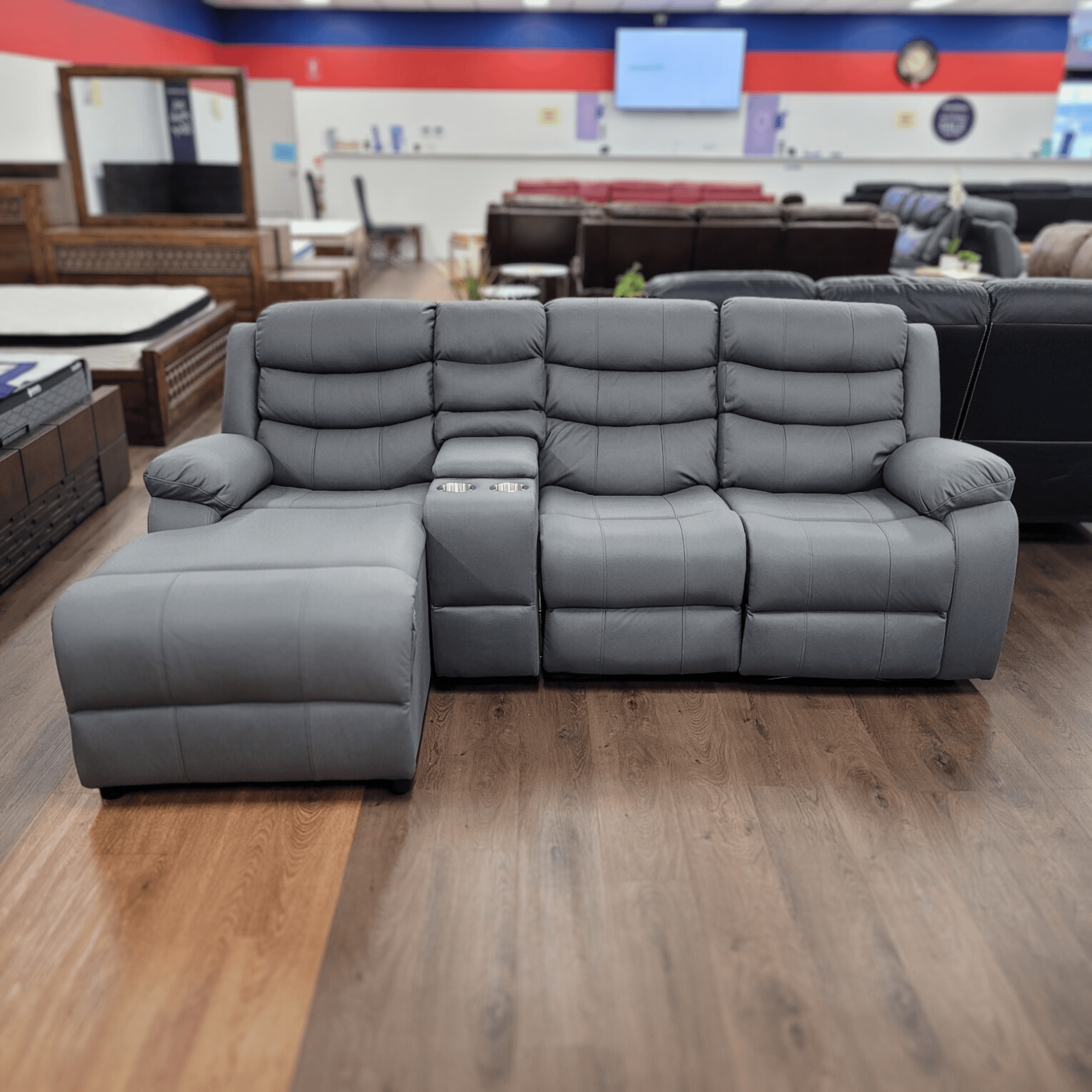 Modern grey sectional sofa with chaise and cup holder in a furniture showroom