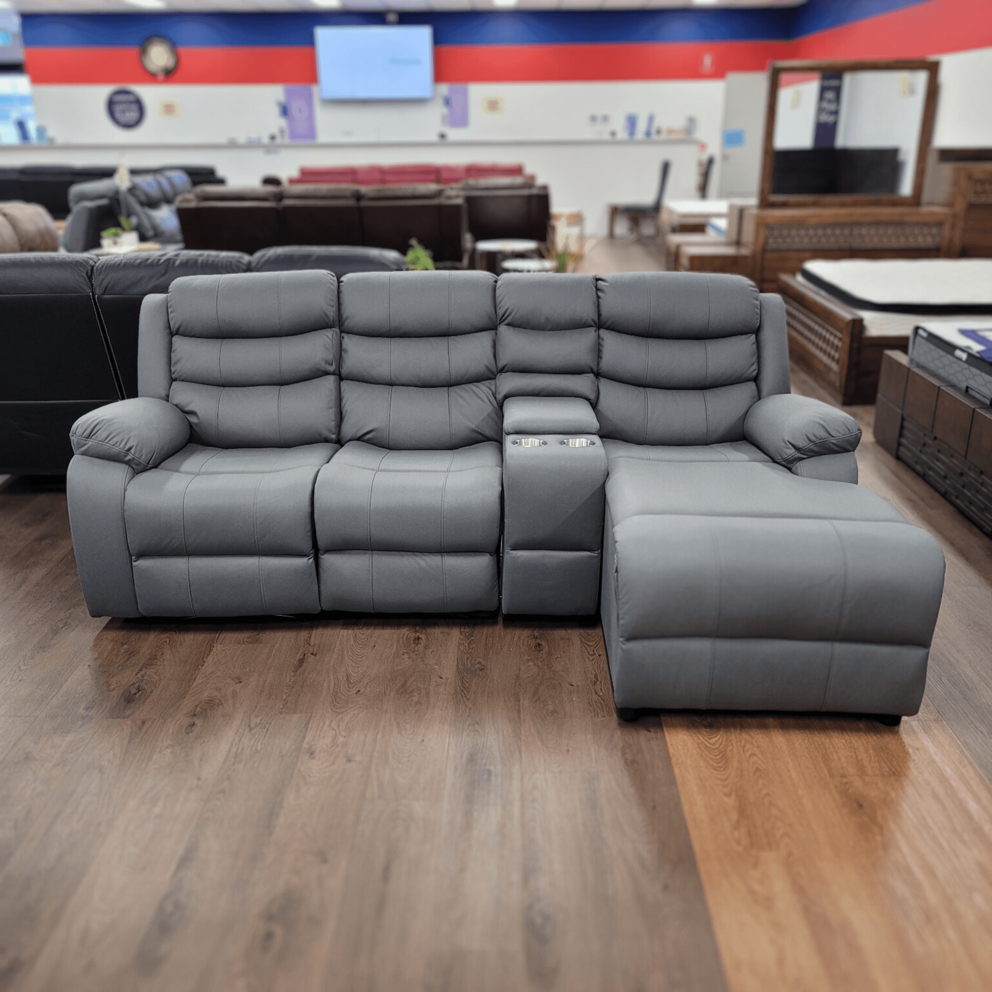 Modern grey sectional recliner lounge with built-in cup holders on showroom floor