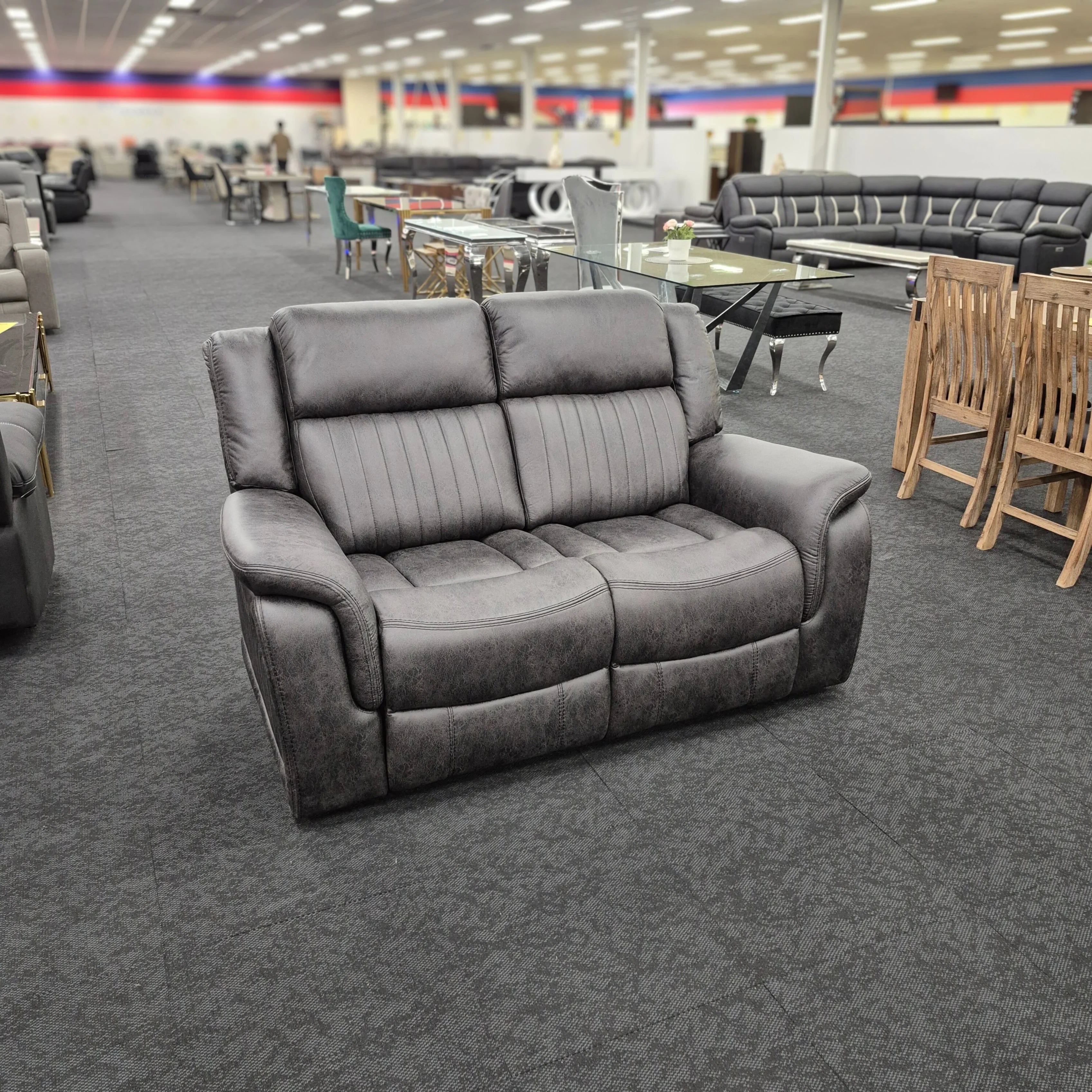 Modern grey 2 seater recliner lounge on display in a furniture showroom