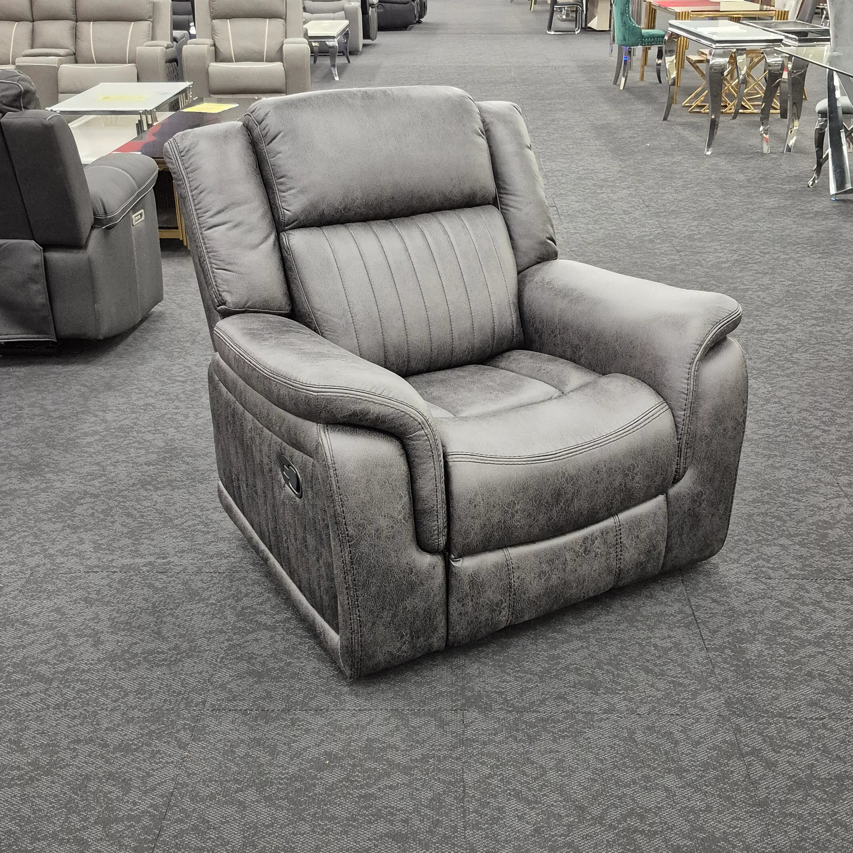 Modern grey recliner armchair with plush cushions in a showroom setting.