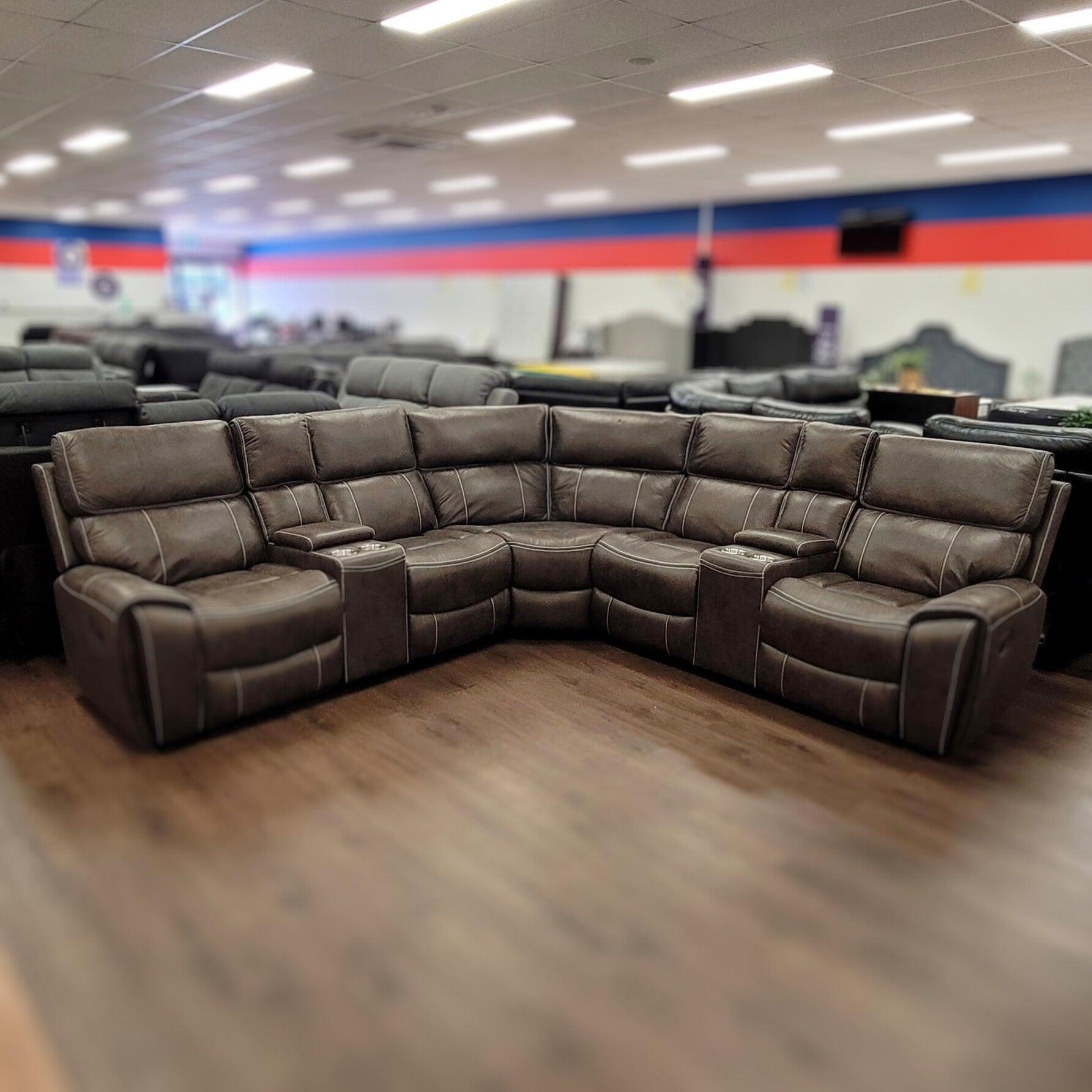 Brown leather corner recliner lounge suite with cup holders in furniture showroom