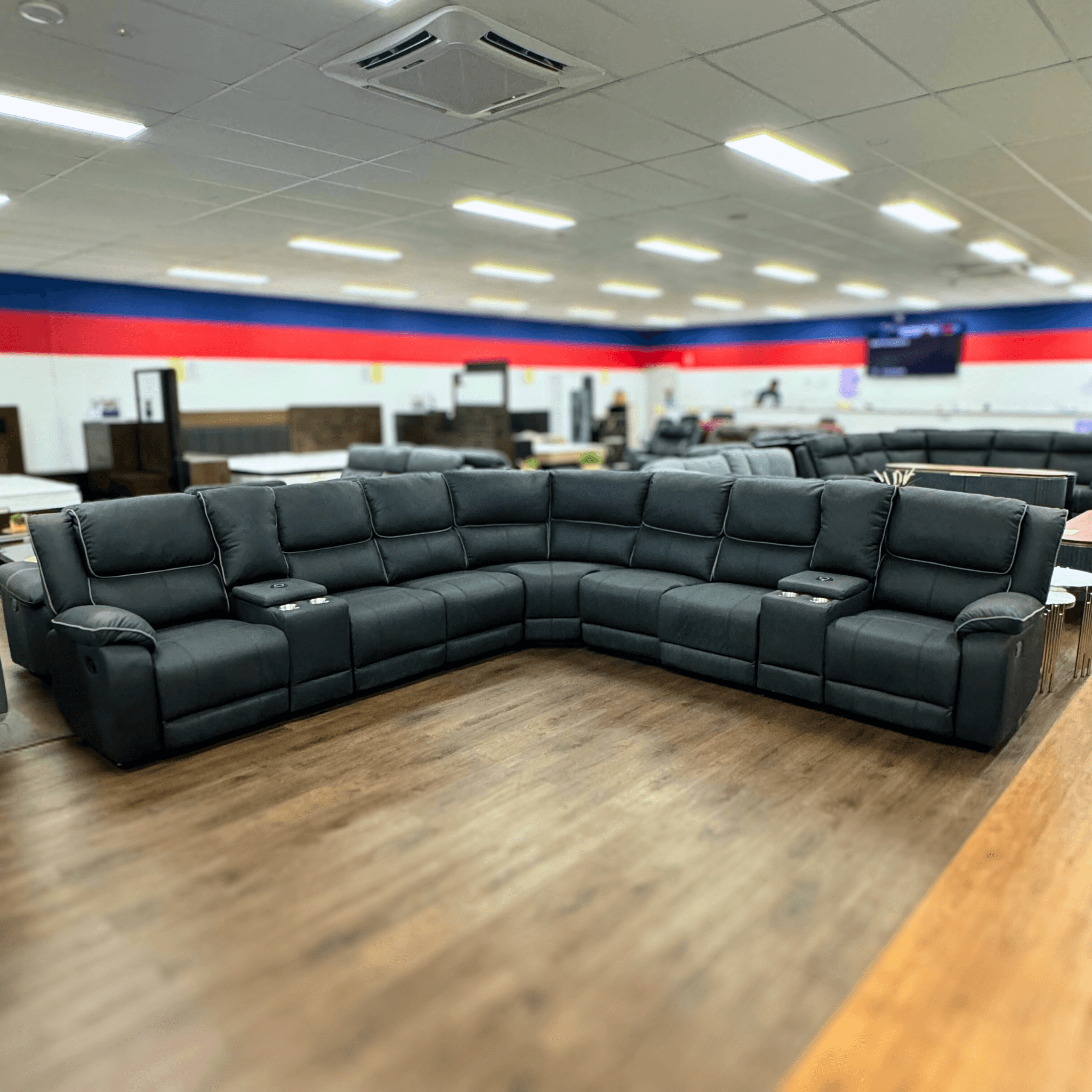 Large black U-shaped recliner sectional sofa with cup holders in a furniture showroom