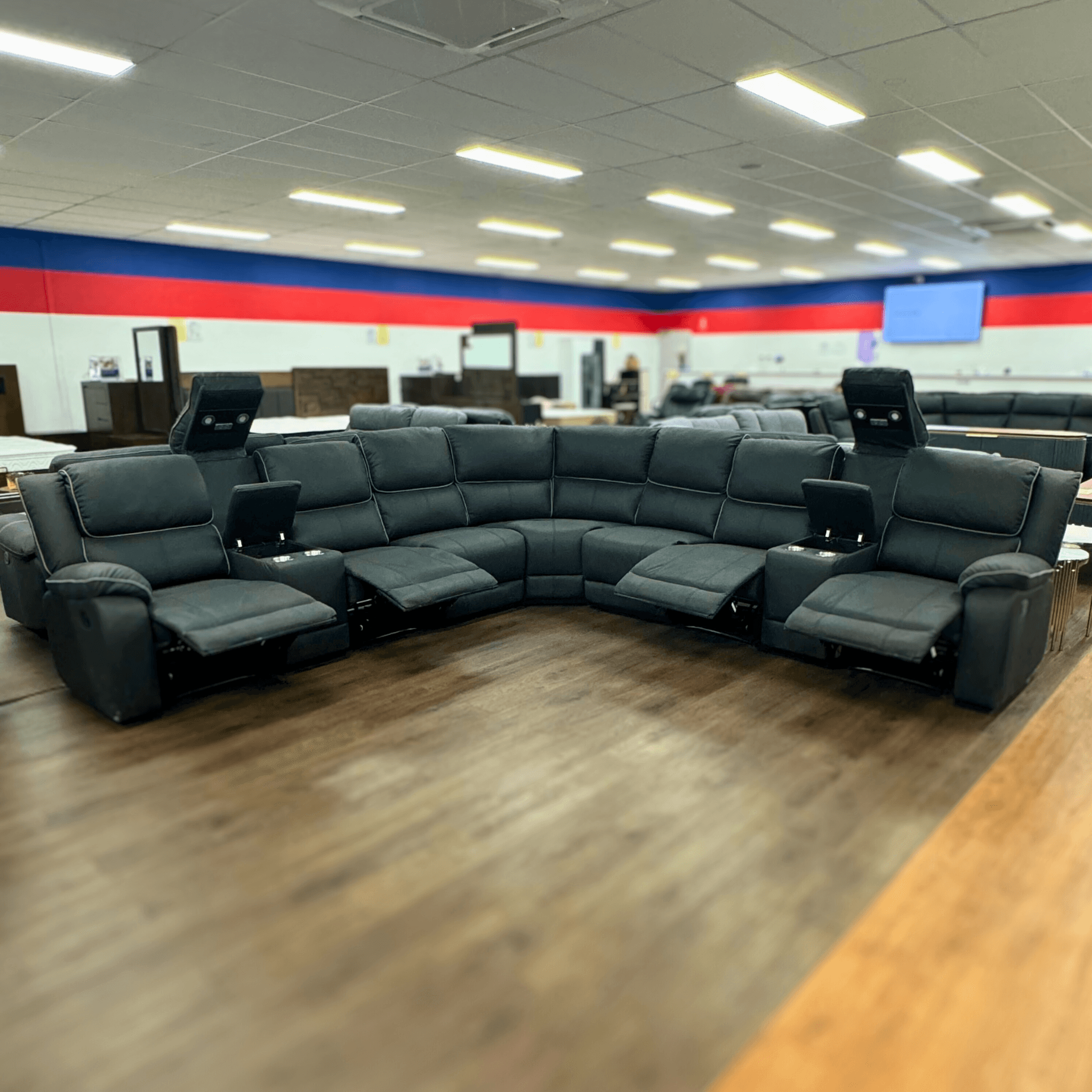 Modern black sectional recliner sofa with LED lights and cup holders in showroom