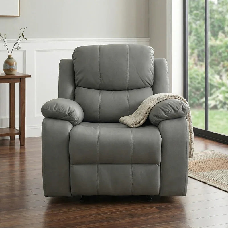Bliss Recliner Chair in gray leather with plush cushions, placed on wooden flooring near a window, featuring a beige throw draped over one armrest in a cozy living space.