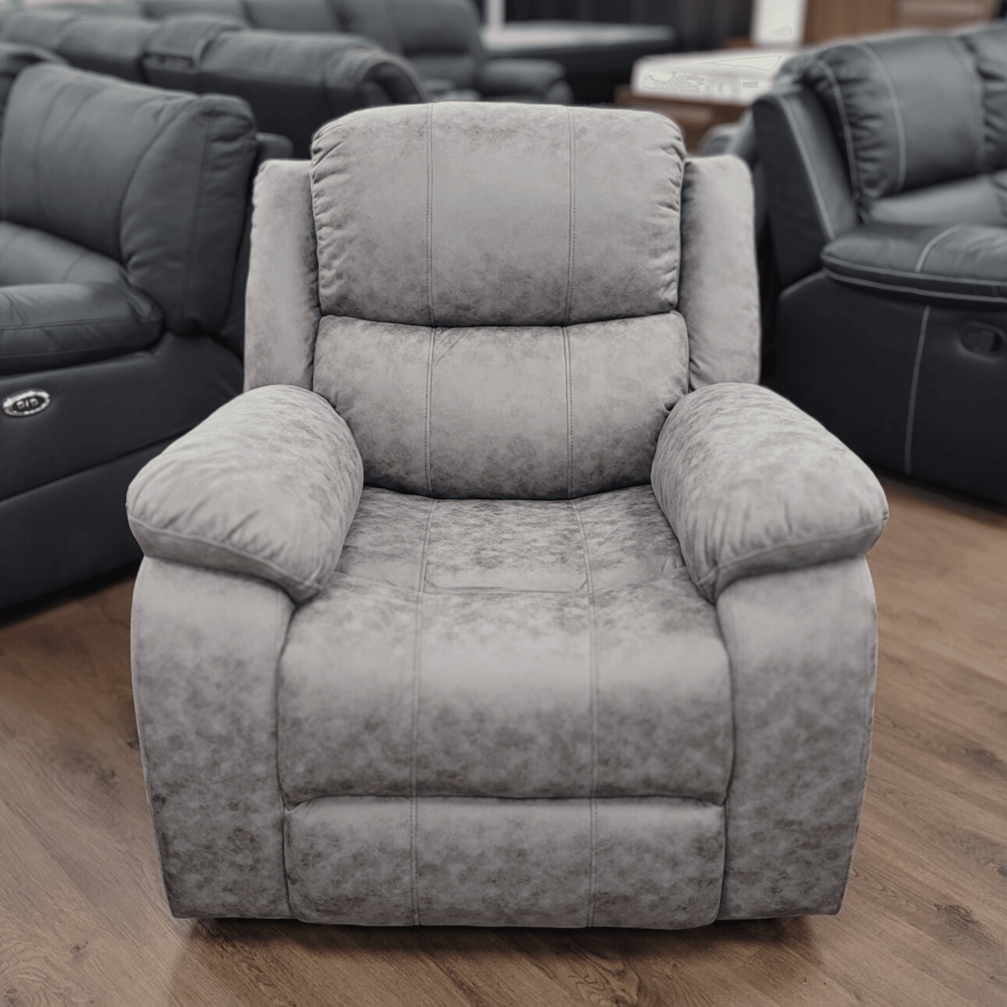 Grey recliner chair with plush padding on wooden floor in a furniture showroom