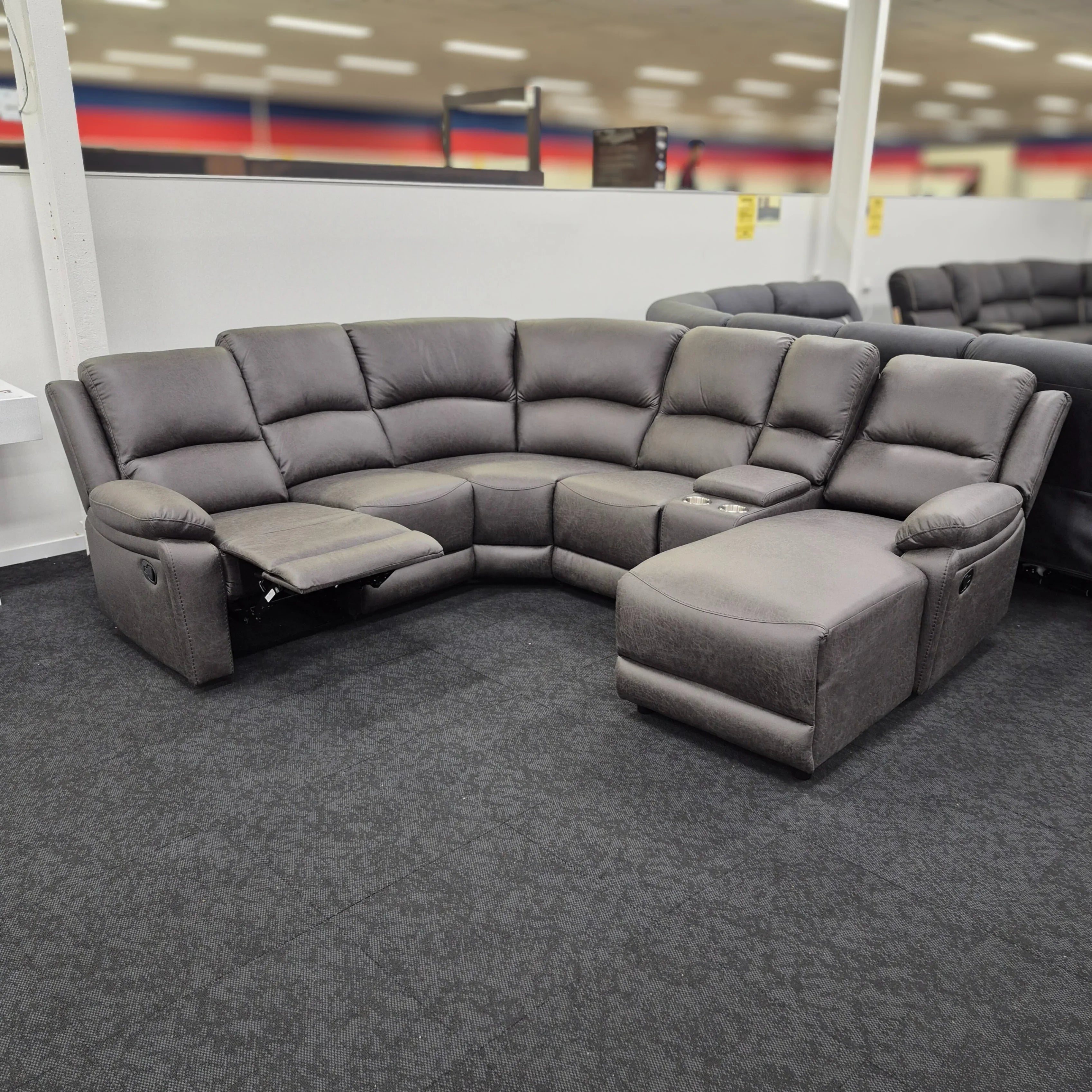 Gray sectional sofa in a store setting with colorful walls in the background