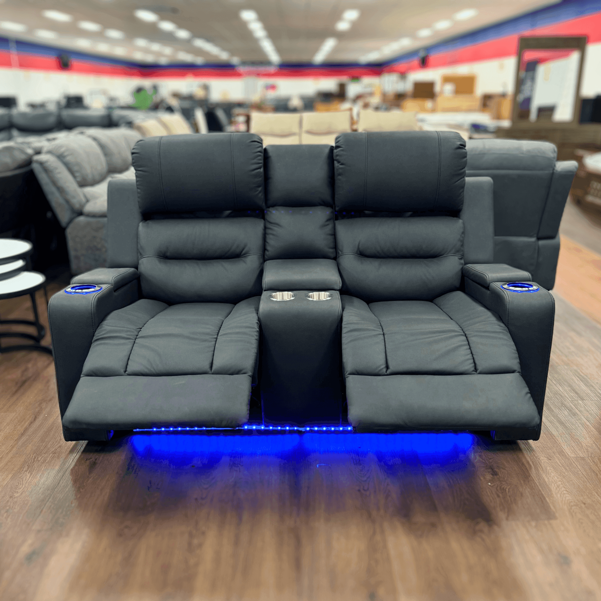 Black two-seater recliner sofa with cup holders, blue LED lighting, and footrests extended
