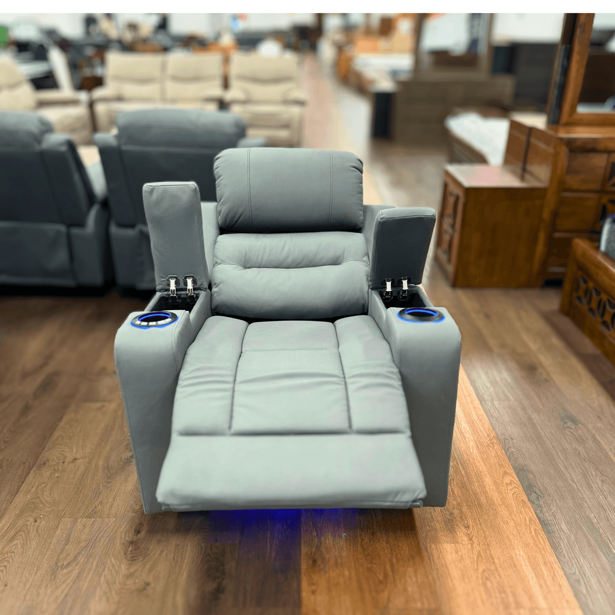 Grey dual motor electric recliner chair with cup holders and LED lighting on showroom floor