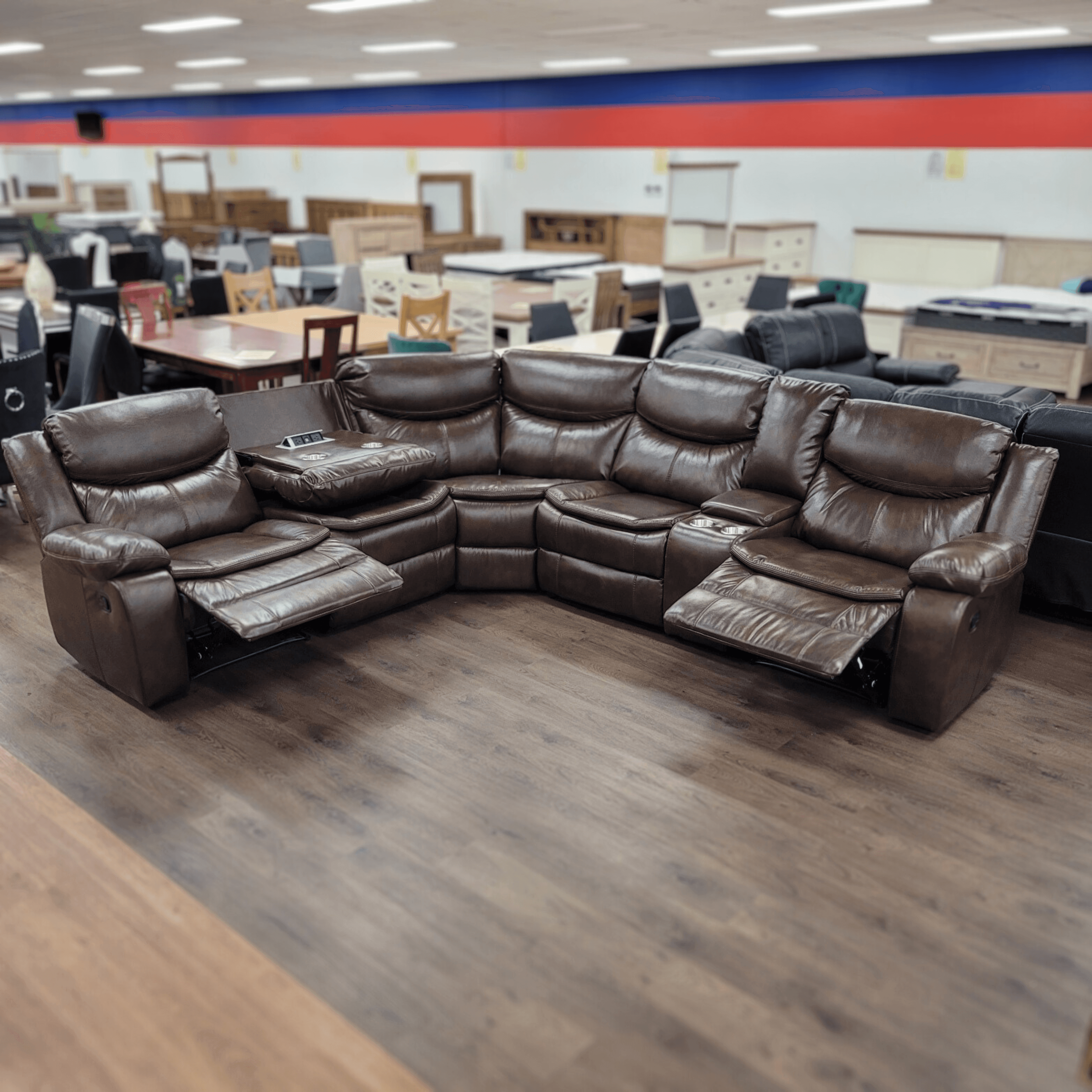 Brown leather reclining sectional sofa with cup holders in a furniture showroom