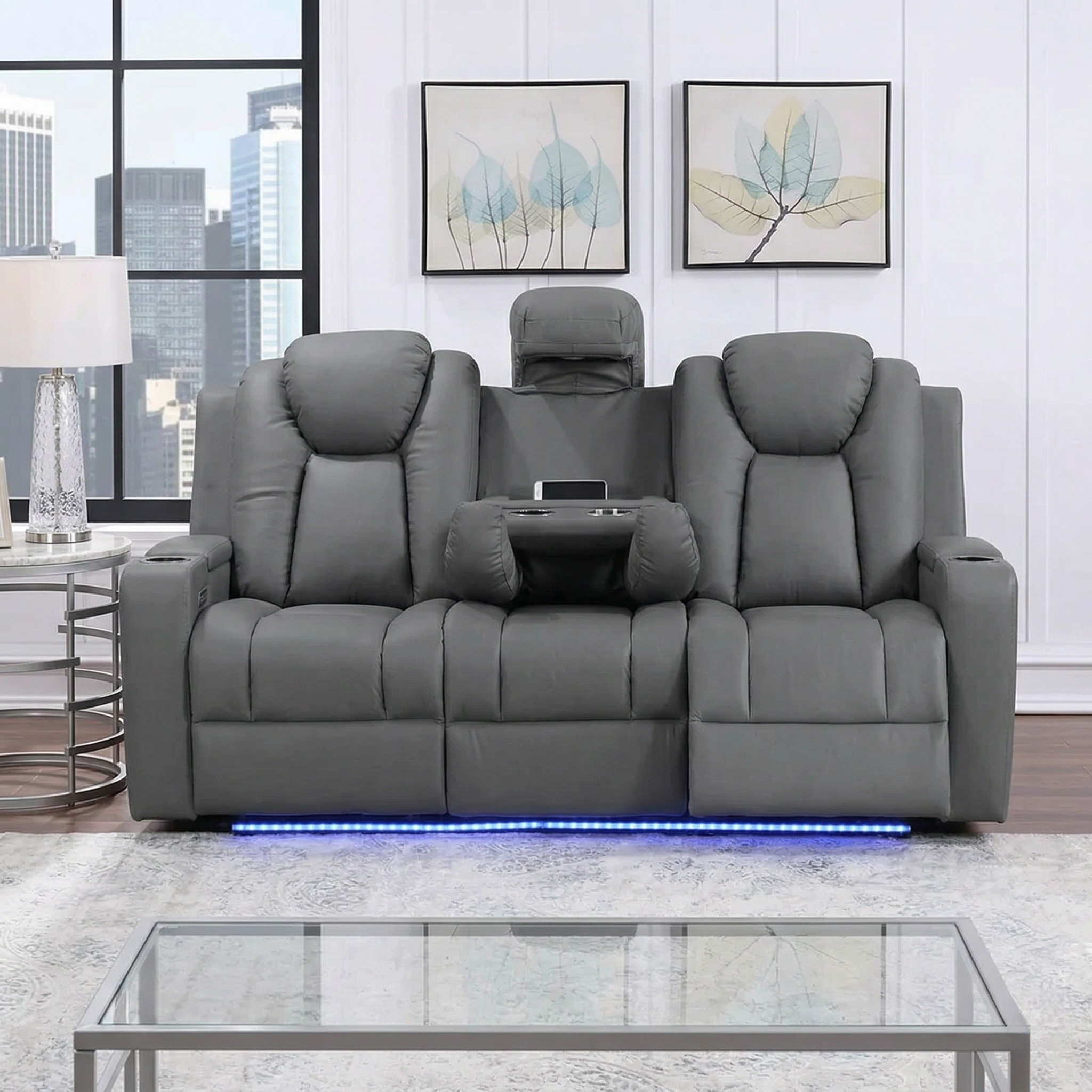 Breeze 3 Seater Dual Motor Electric Recliner Lounge in dark grey leather with cup holders, LED lighting underneath, and a modern living room background featuring cityscape windows and minimalist decor.