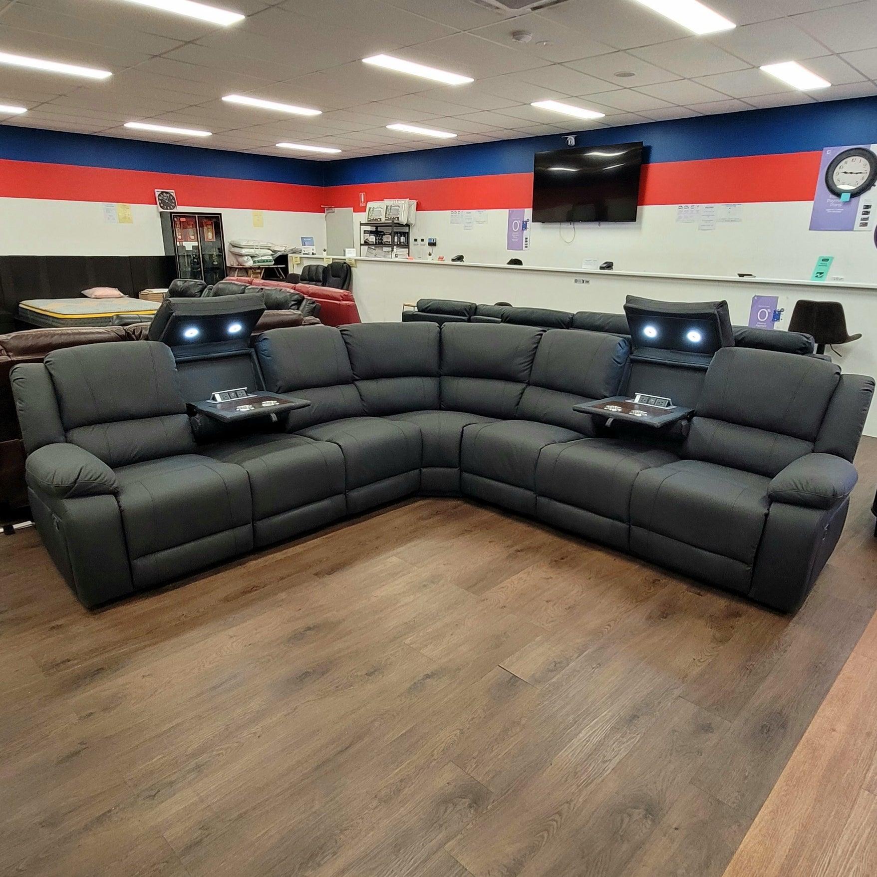 Modern black reclining sectional sofa with built-in cup holders and LED lights in showroom