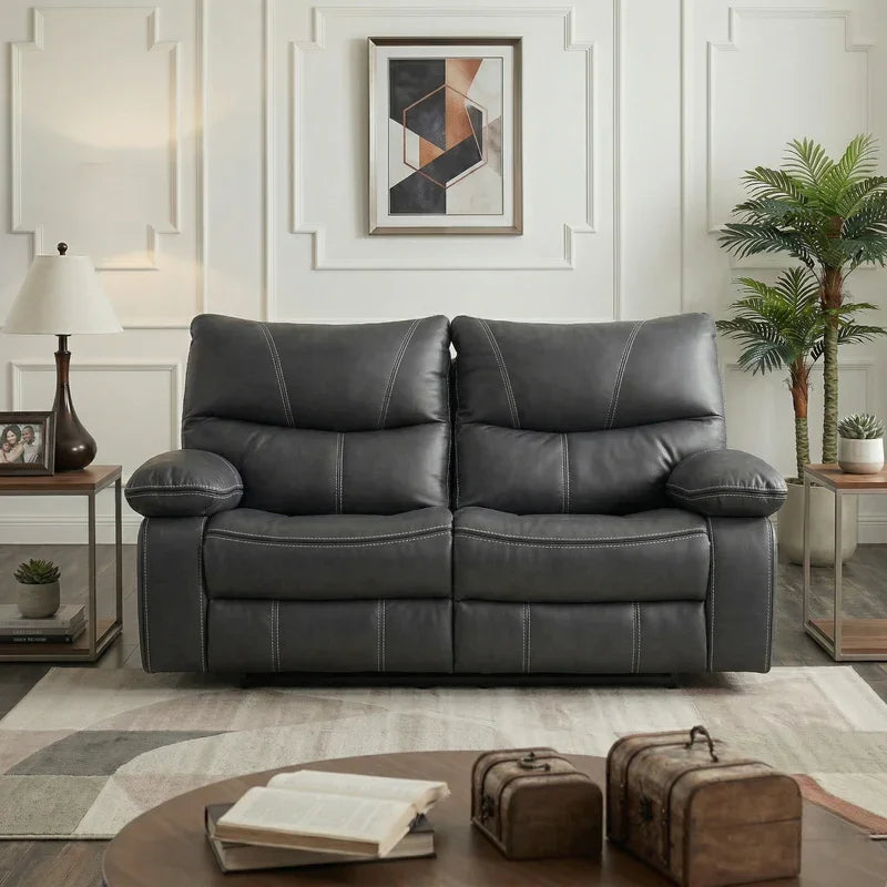 Brooke 2 Seater Recliner Lounge in dark grey leather with plush cushioned seats and armrests, placed in an elegant living room setting with wall art and side tables.