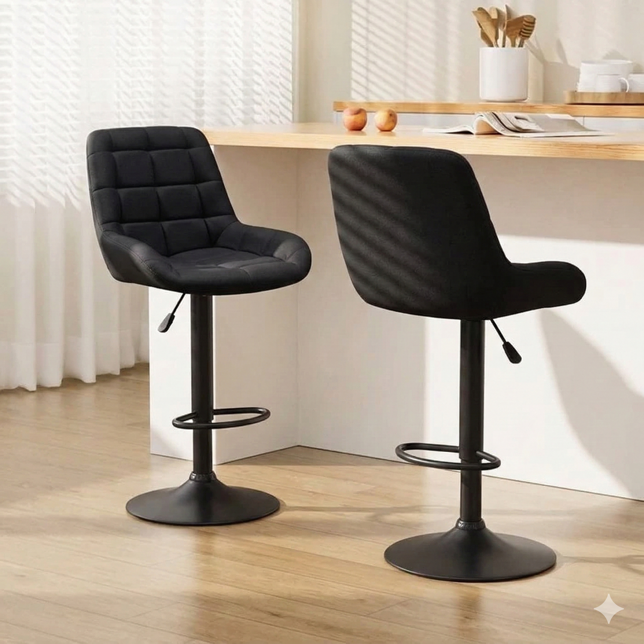 Modern black bar stools with padded seats at a light wood kitchen counter in a bright room