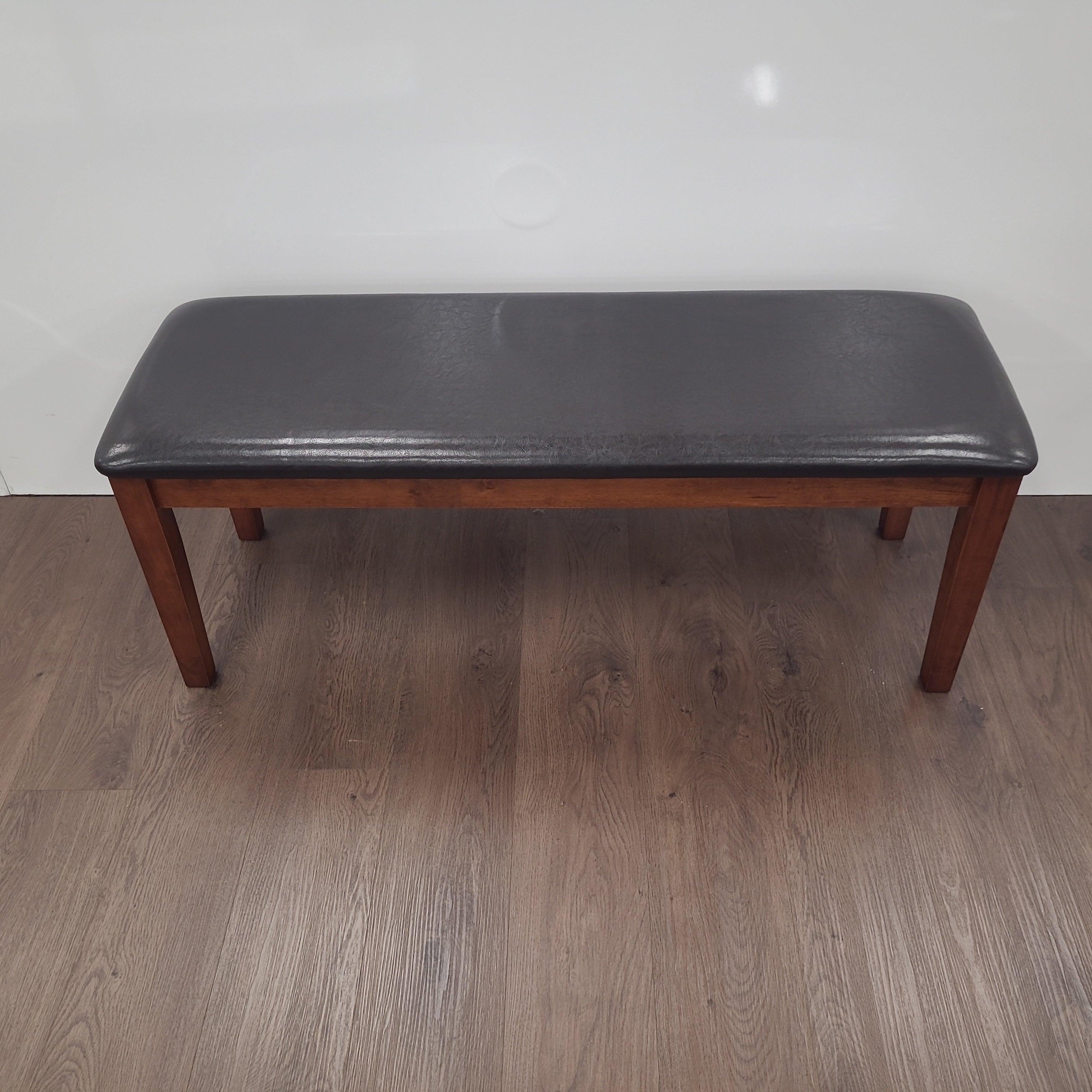 Modern dining bench with black upholstered seat and wooden legs on timber flooring