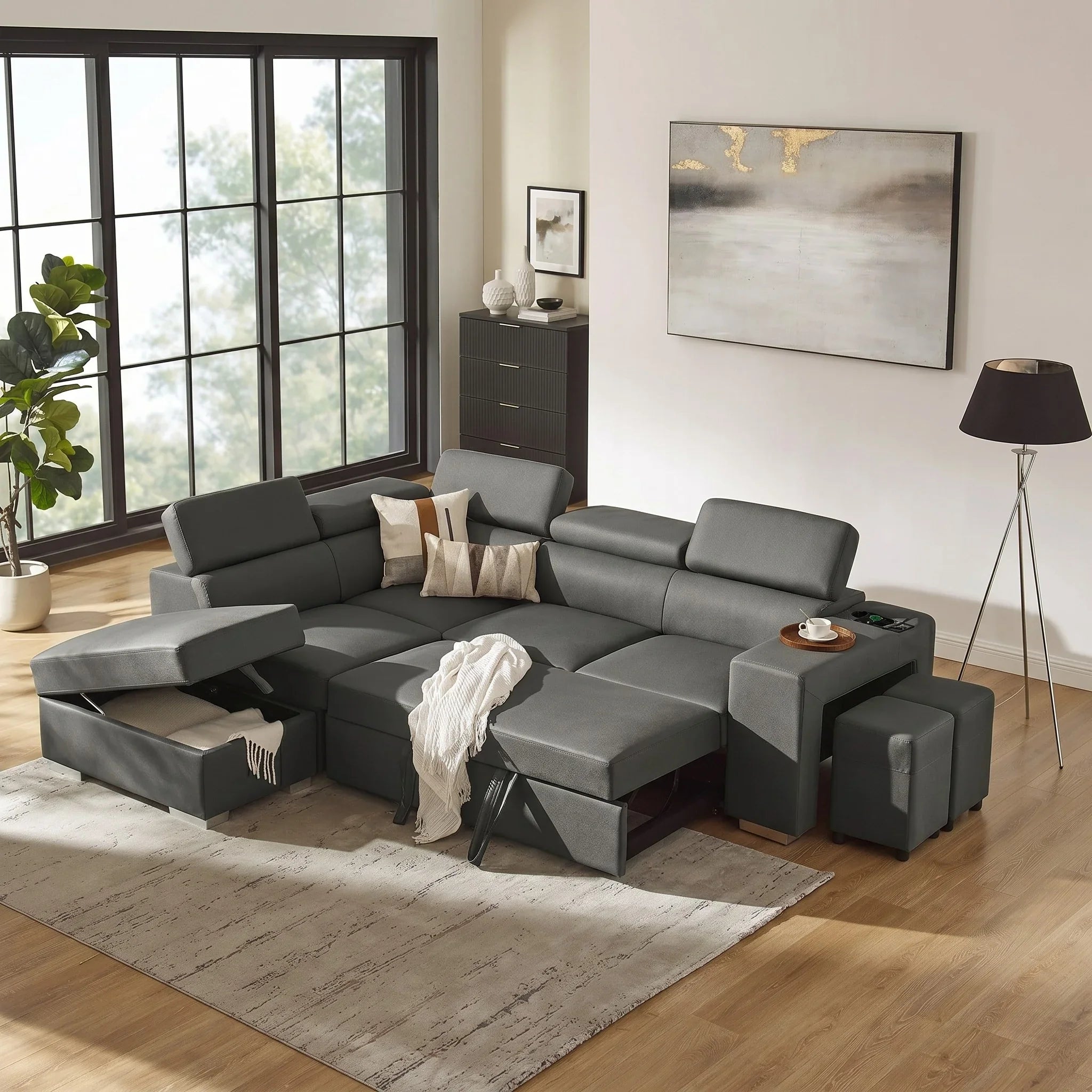 Gray sectional sofa bed in a living room with a rug, lamp, and painting.