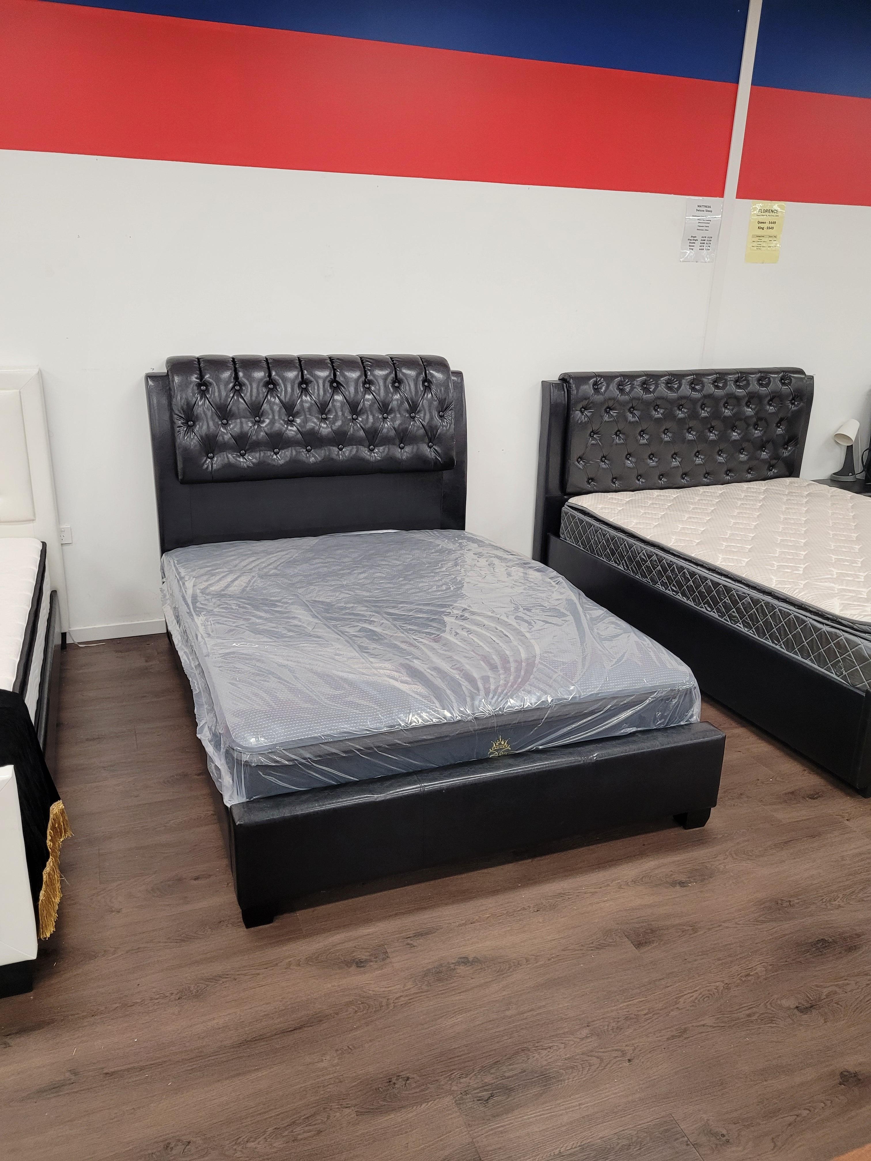Black tufted bed frame and mattress on wooden floor in furniture showroom