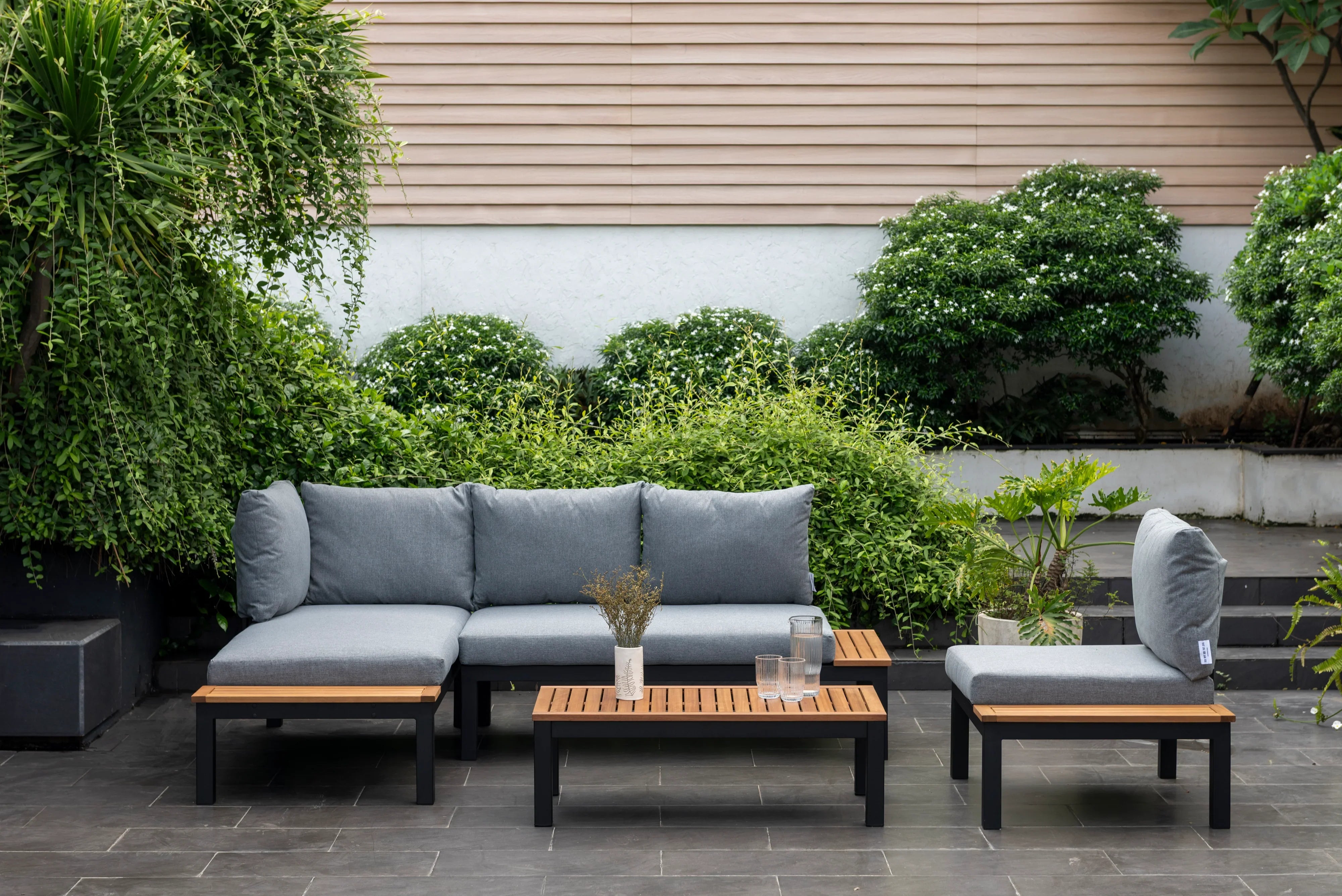 Modern outdoor patio sofa set with grey cushions and wooden coffee table in garden setting