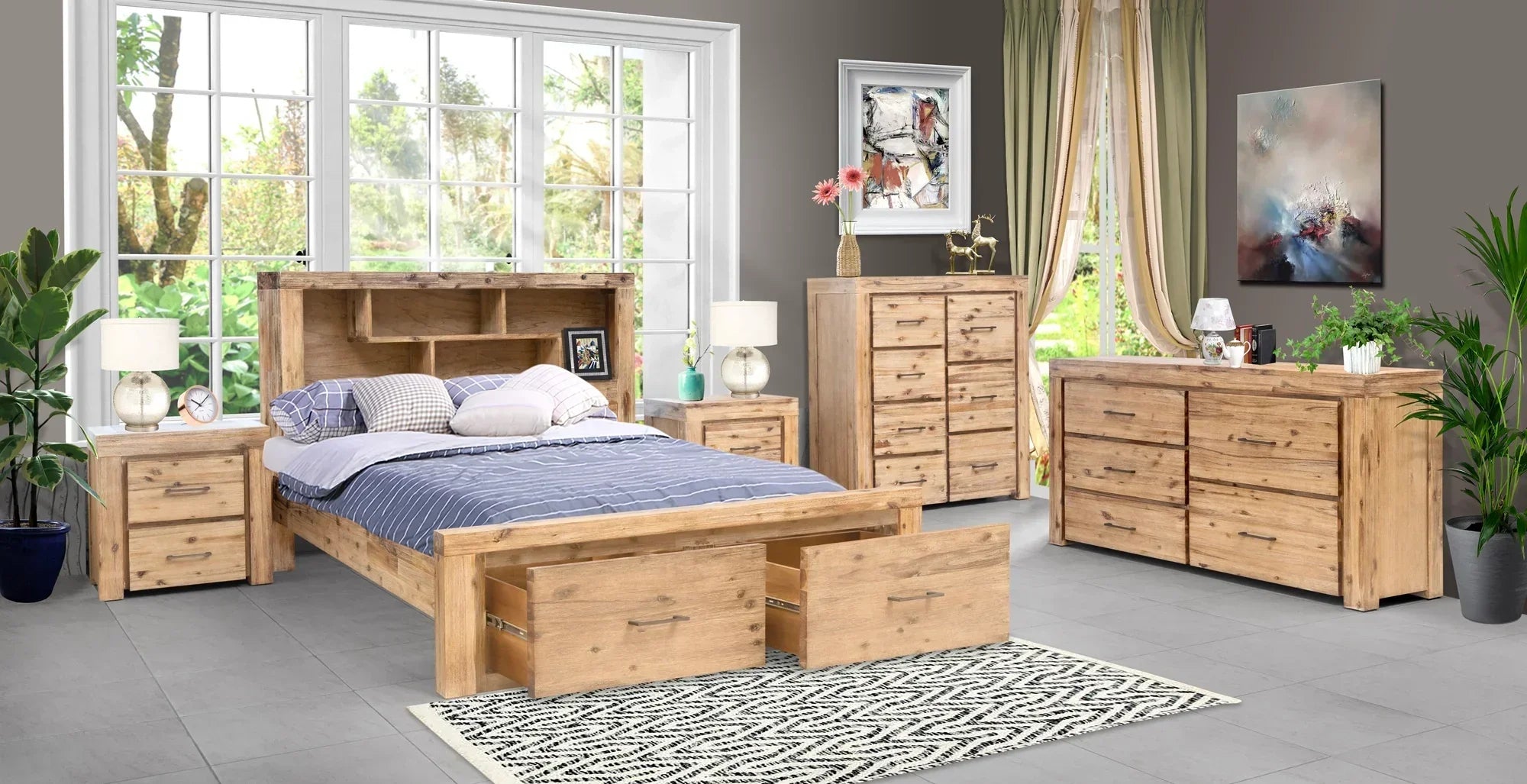 Wooden bedroom furniture set with bed, dressers, and nightstands in a room with large windows.