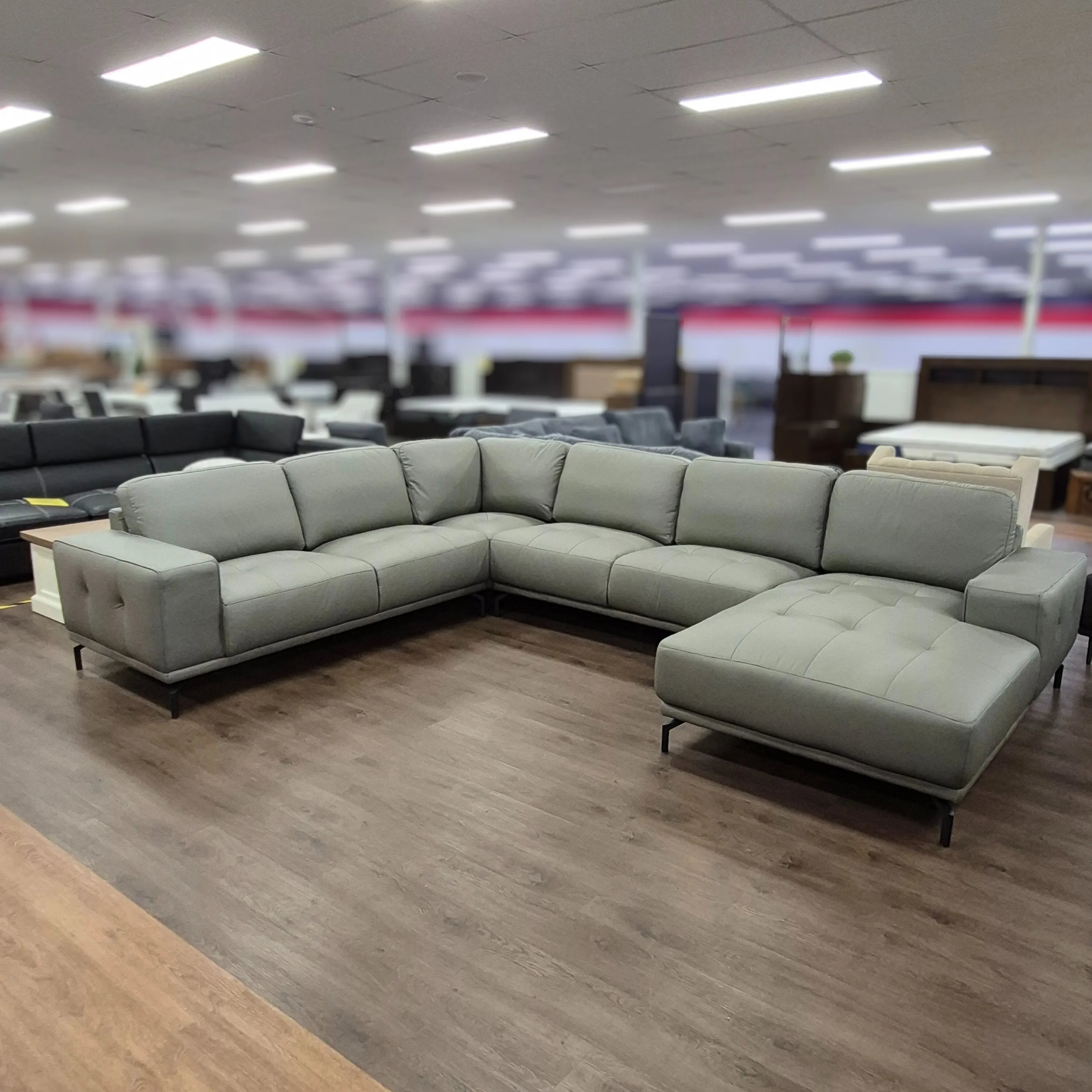 Modern grey corner leather lounge with chaise in spacious showroom