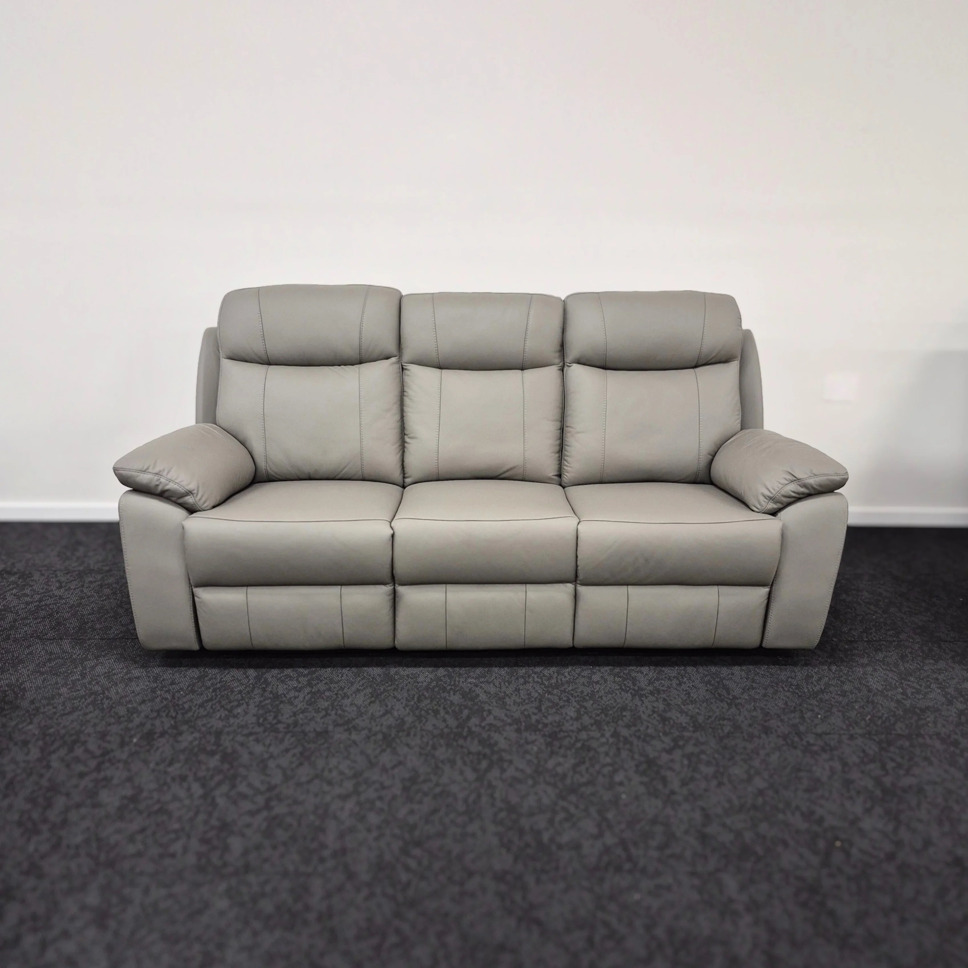 Grey leather 3 seater recliner lounge sofa with padded arms in a modern living room