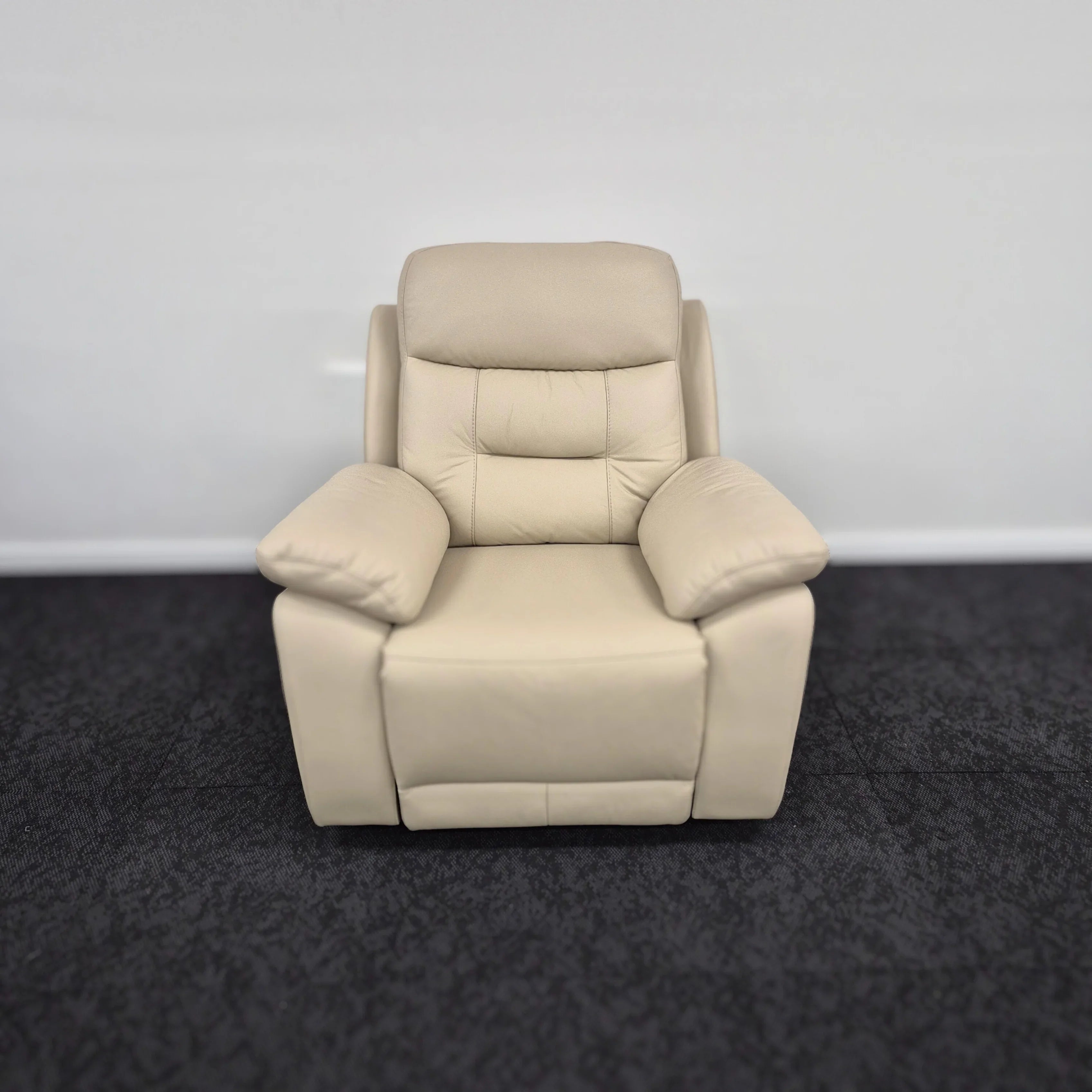 Beige leather recliner chair with padded arms and backrest on dark carpet