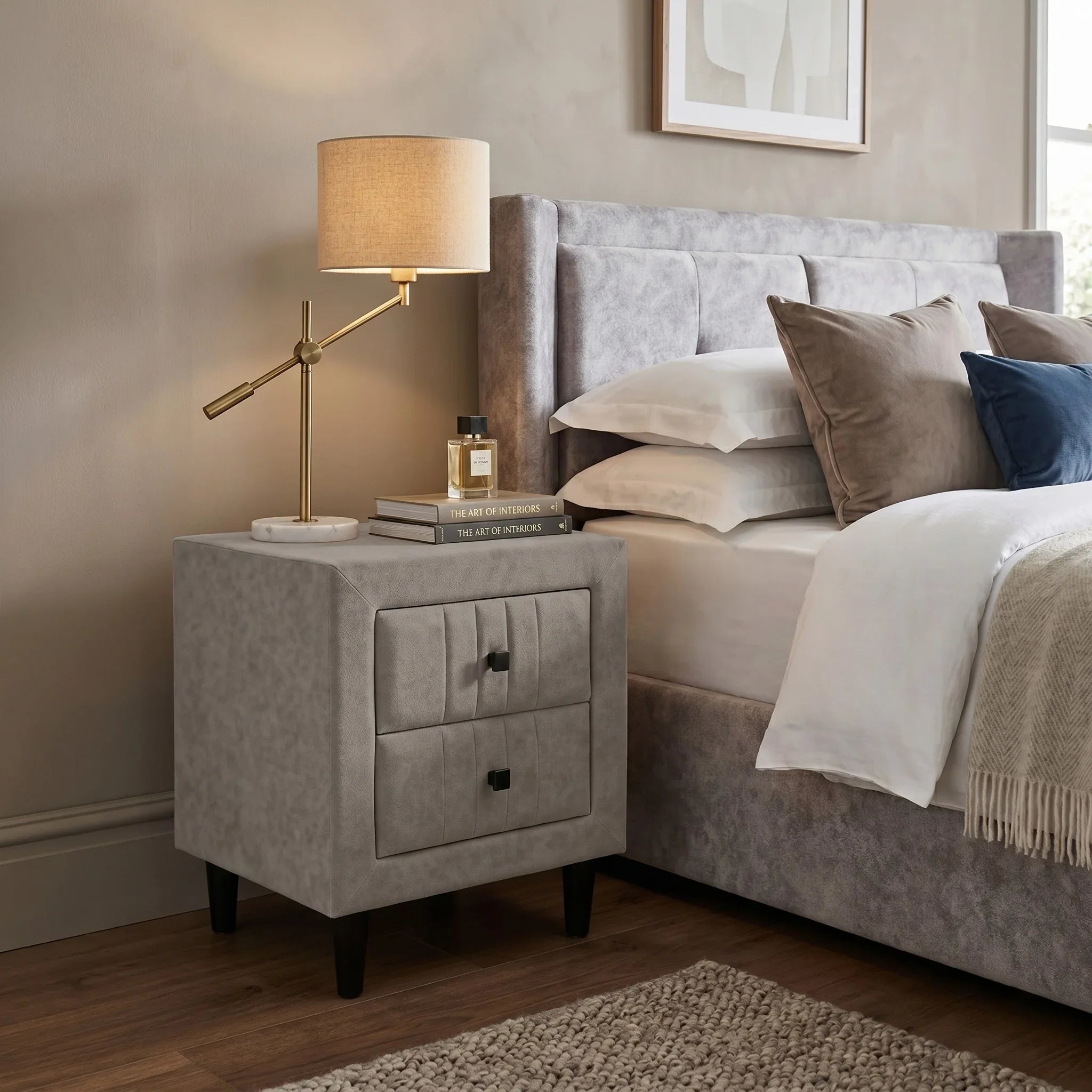 Light Gray upholstered nightstand next to a bed with pillows and a lamp.