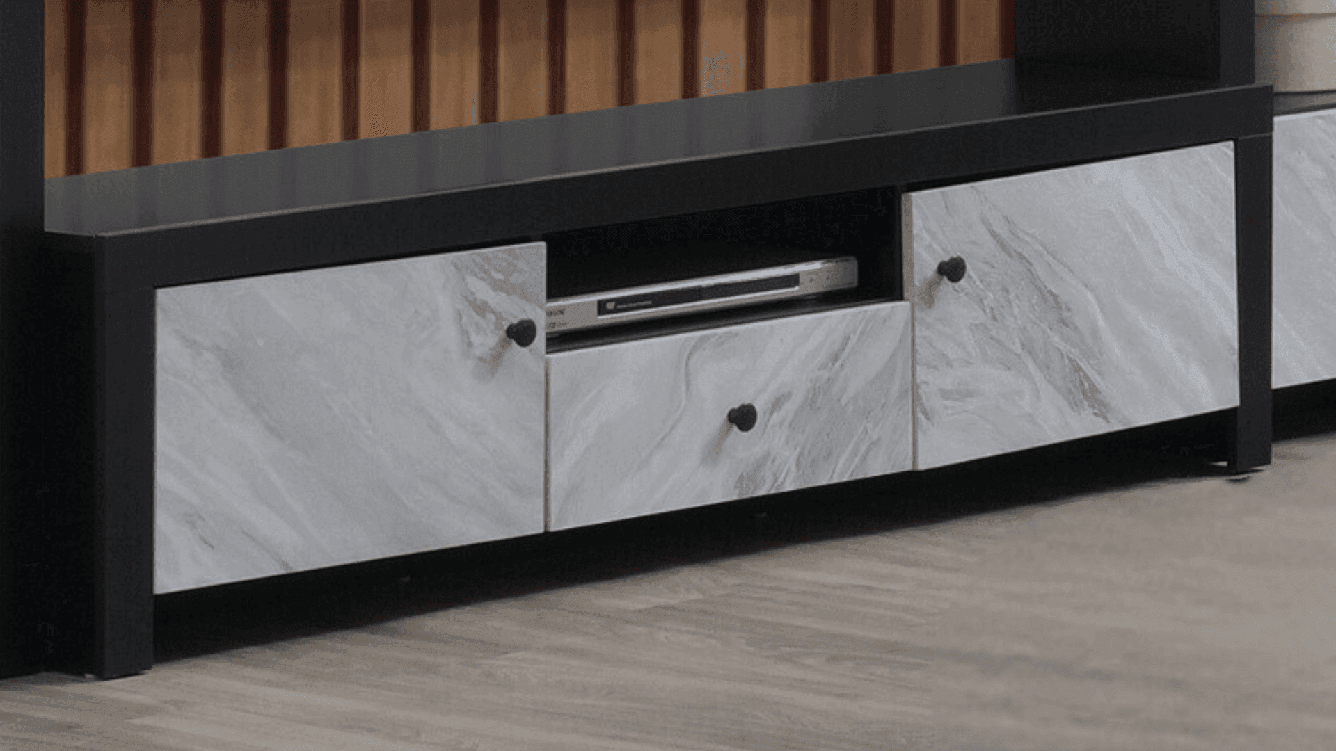 Modern TV unit with black frame, marble-patterned drawers, on wood flooring