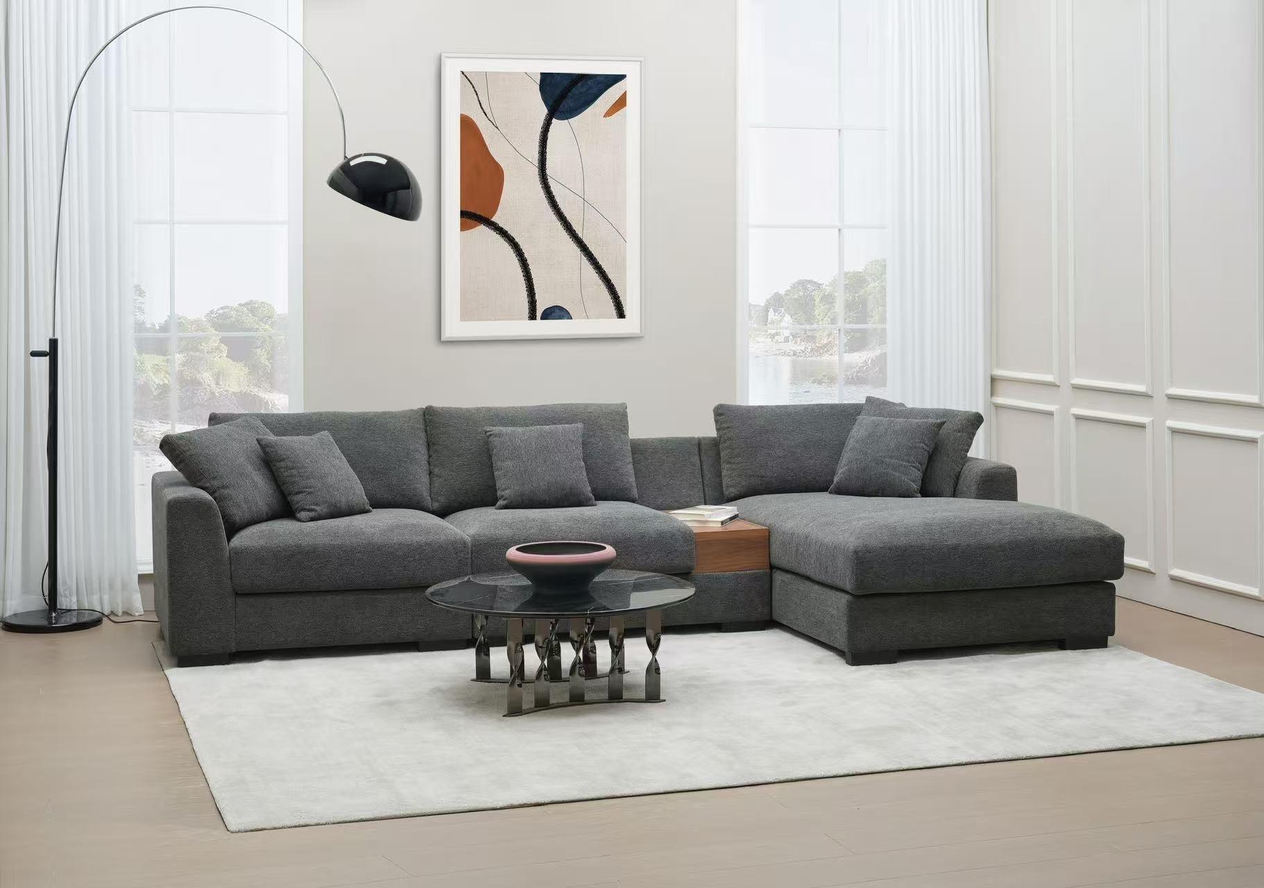Modern living room with dark grey sectional sofa, glass coffee table, and abstract wall art.