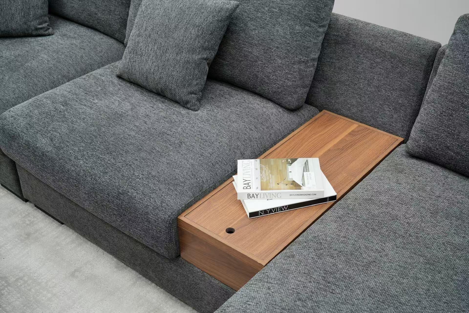 Grey fabric sectional sofa with built-in wooden table and cushions, magazines on table