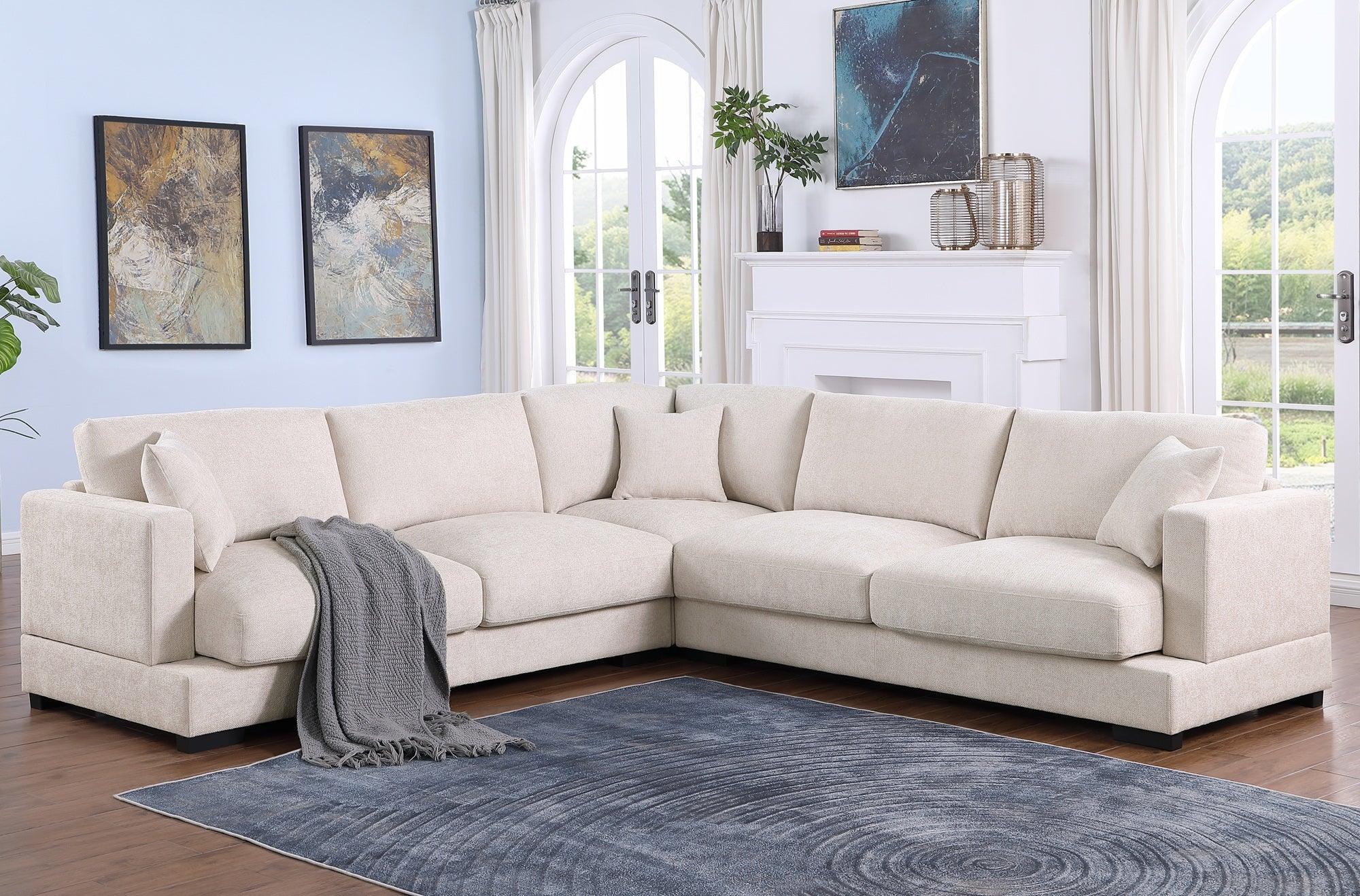 Modern beige corner sectional sofa in bright living room with blue rug and abstract wall art