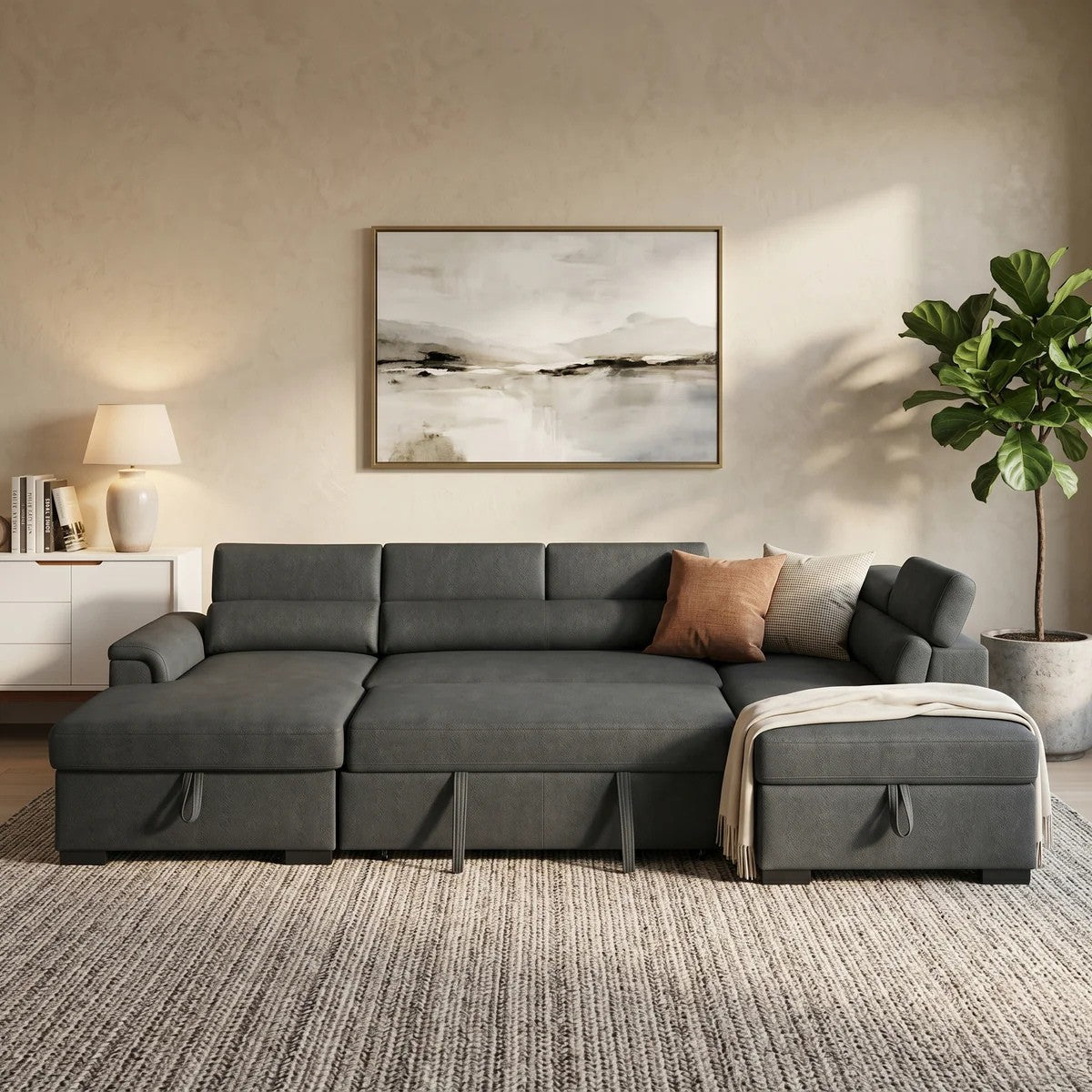 Modern grey fabric Omaha Pull-Out Sofa Bed with adjustable headrests and storage ottoman in a cozy living room setting with neutral decor and plants.