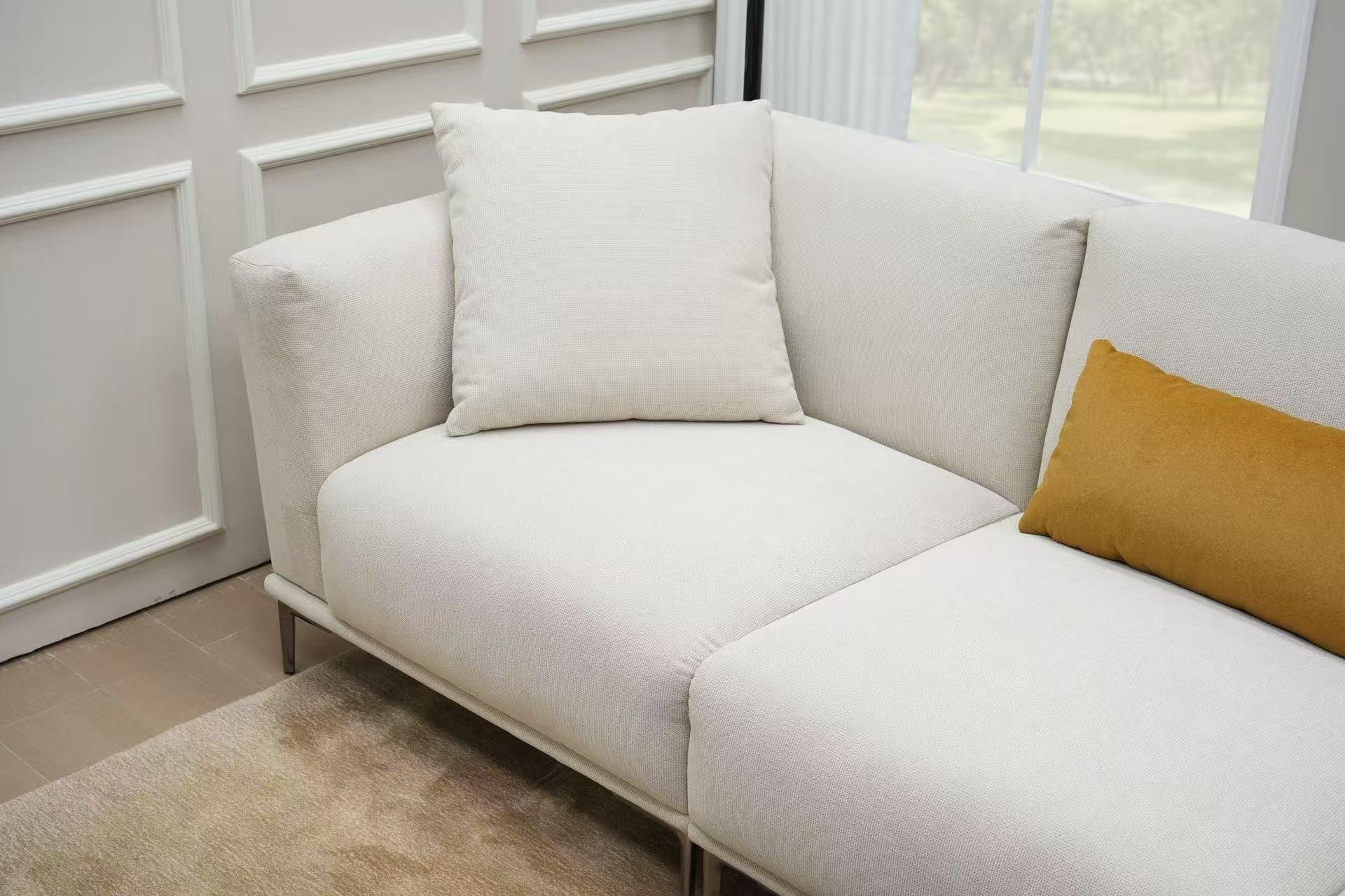 Modern cream fabric corner sofa with beige and yellow cushions in a bright living room