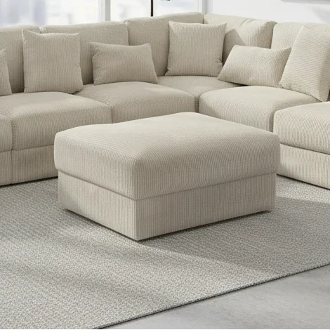 Beige sectional sofa with matching ottoman on a gray rug
