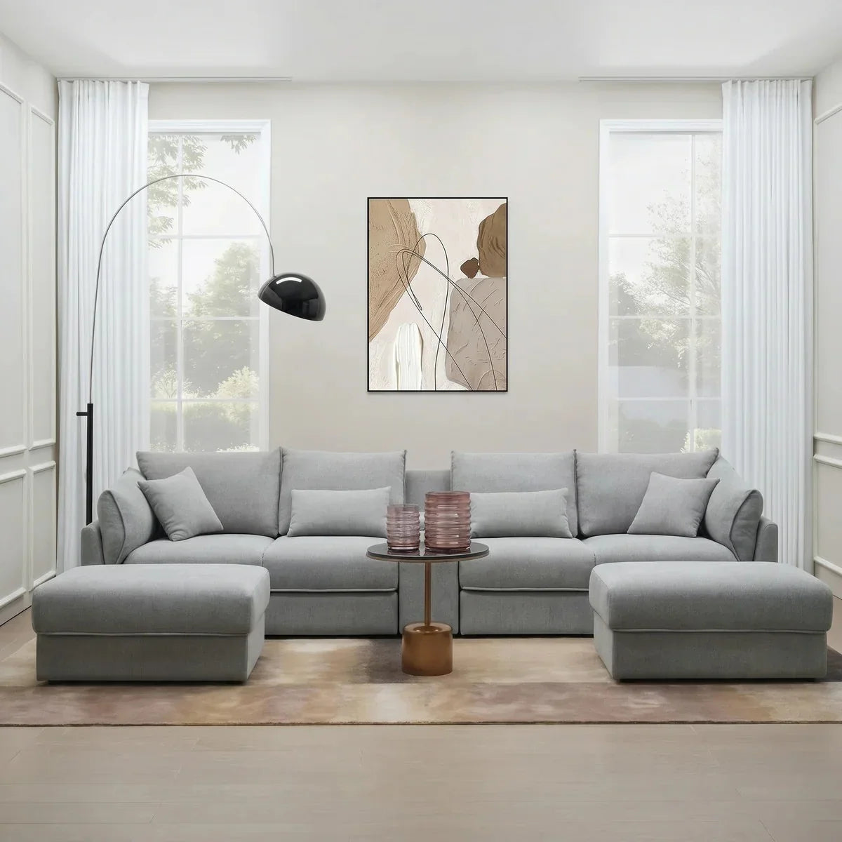 Modern living room featuring a light gray Oracle 4 Seater Sofa with Ottoman, complemented by neutral tones, large windows, minimalist decor, and a sleek floor lamp.